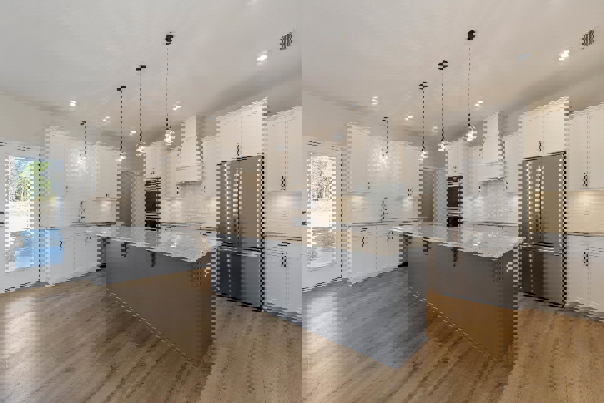 Spacious kitchen featuring a marble-topped island, stainless steel refrigerator and oven, white cabinetry, glass-paneled door, pendant ceiling light, and light-colored walls and