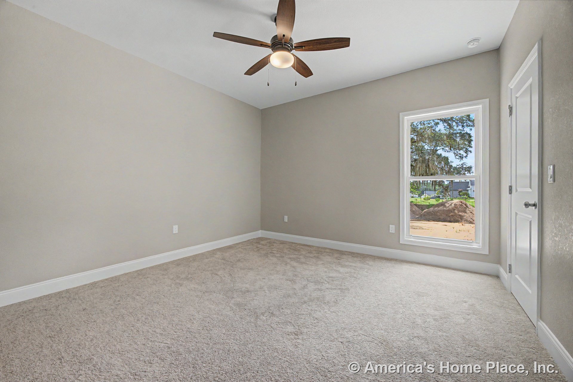 Bedroom with beige carpet flooring, neutral wall paint, white baseboards, large single window with white trim, ceiling fan and light fixture, paneled interior door, modern