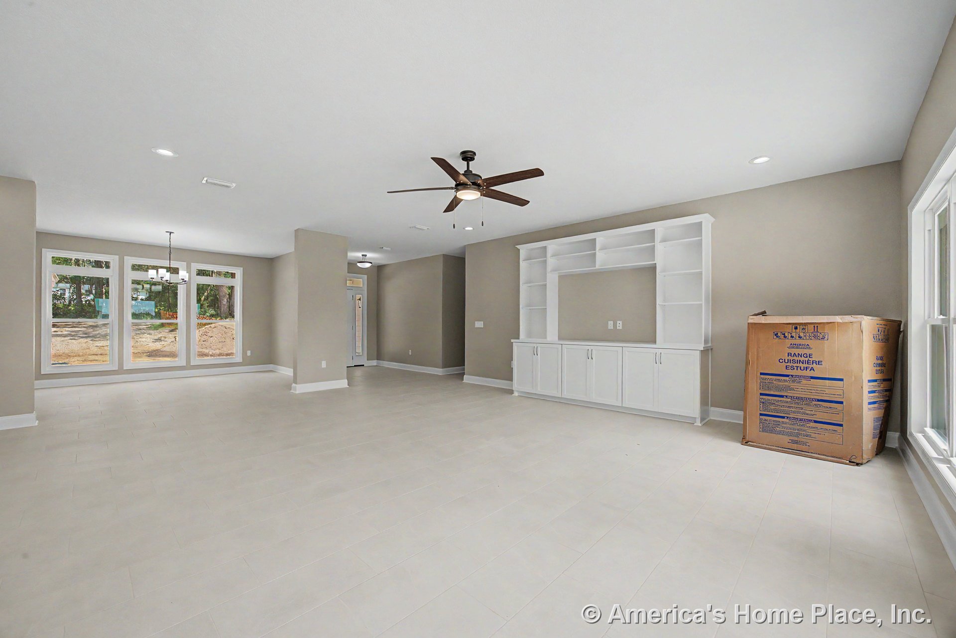 Built-in white entertainment center with cabinetry, expansive picture windows, neutral painted walls, light tile flooring, ceiling fan with integrated light, recessed lighting