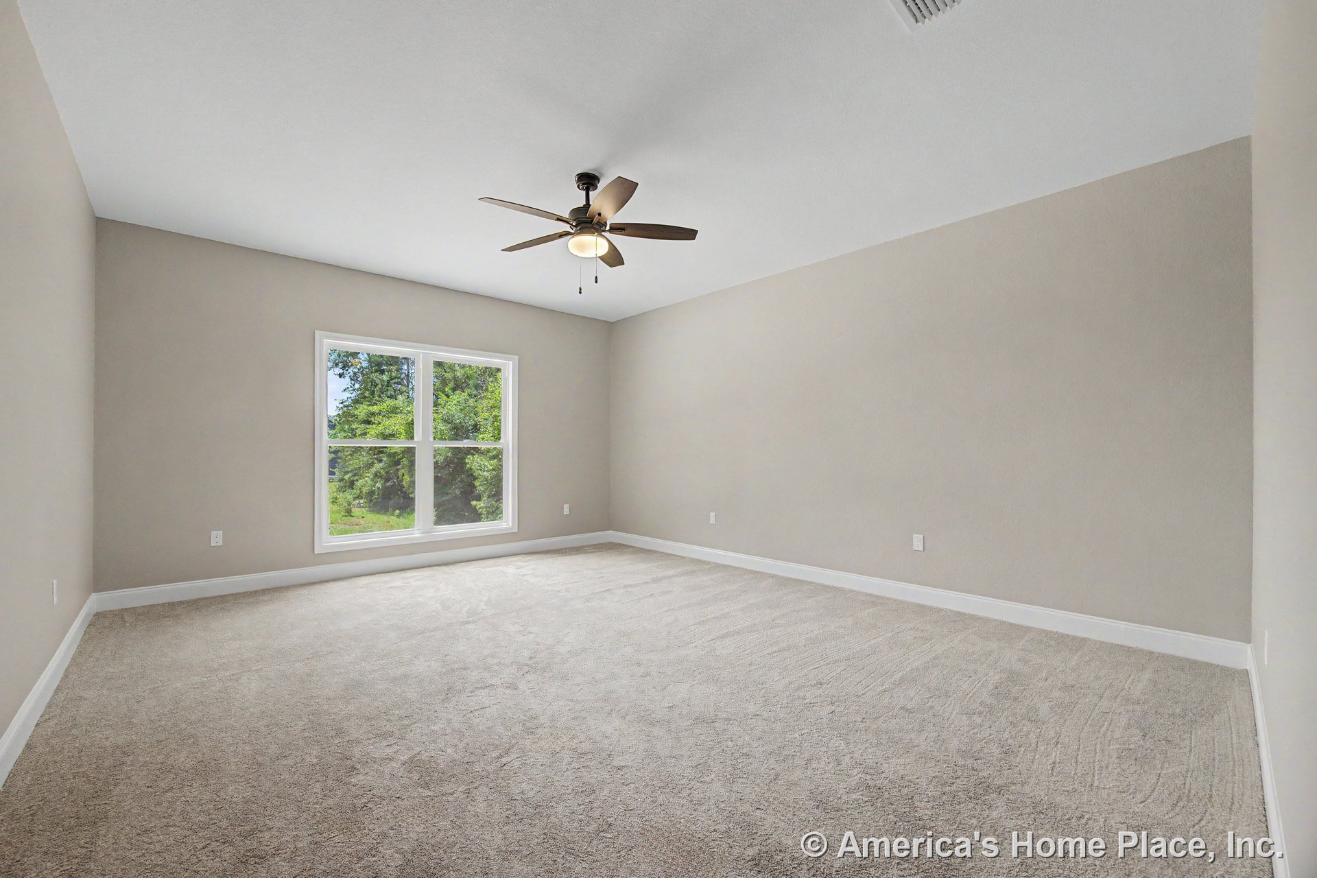 Spacious bedroom with vaulted ceiling, large double window, neutral wall paint, white baseboard trim, light carpet flooring, and ceiling fan with built-in lighting.