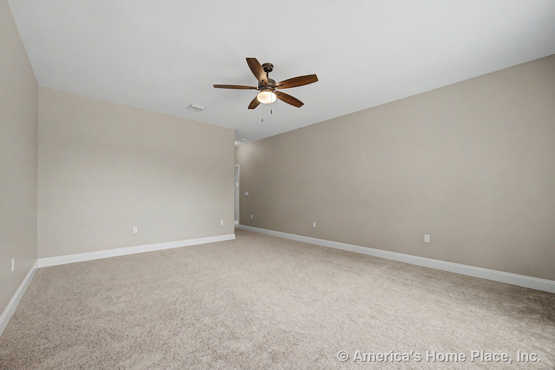 Spacious bedroom with beige carpet flooring, neutral painted walls, white baseboard trim, recessed ceiling, ceiling fan with light fixture, and electrical outlets along the walls.