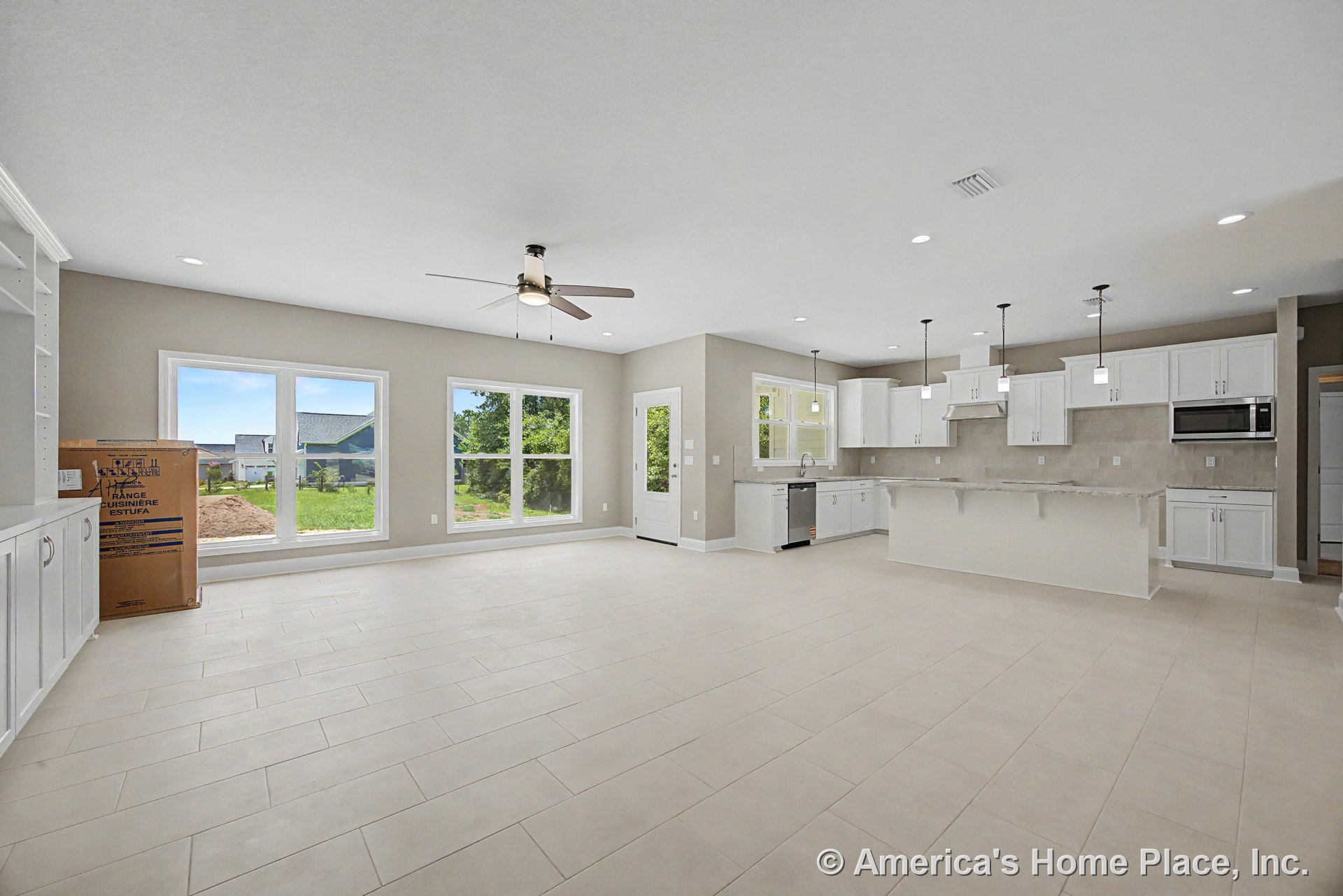 Open-concept kitchen and living area with white shaker cabinets, granite countertops, pendant lights above the island, large tile flooring, built-in shelving, multiple large