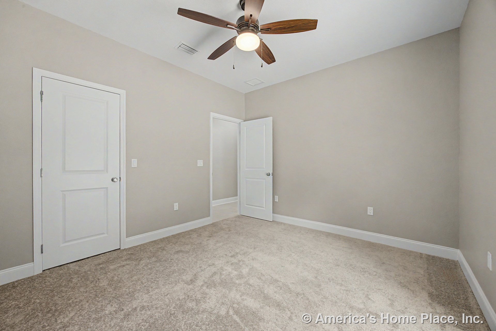 Beige carpet flooring, light gray painted walls, white paneled doors, ceiling fan with integrated light fixture, white baseboard trim, recessed ceiling vent, and neutral color