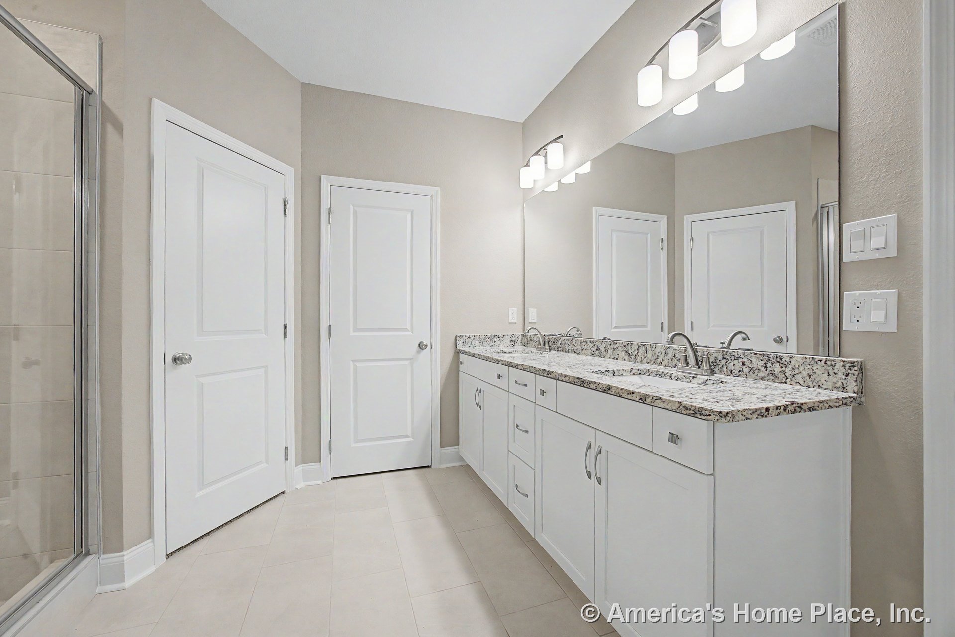 Double vanity with granite countertop, white shaker cabinets, large wall mirror, built-in vanity lighting, tile flooring, chrome faucets, glass shower enclosure, modern trim