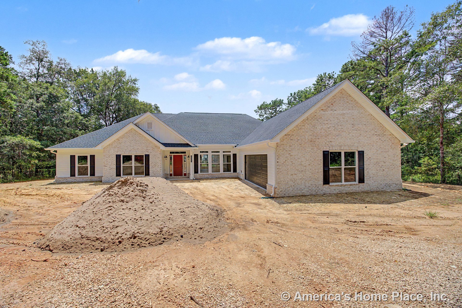 Light brick exterior with black window shutters, covered front porch, red entry door, attached two-car garage, multiple large windows, and paved driveway.
