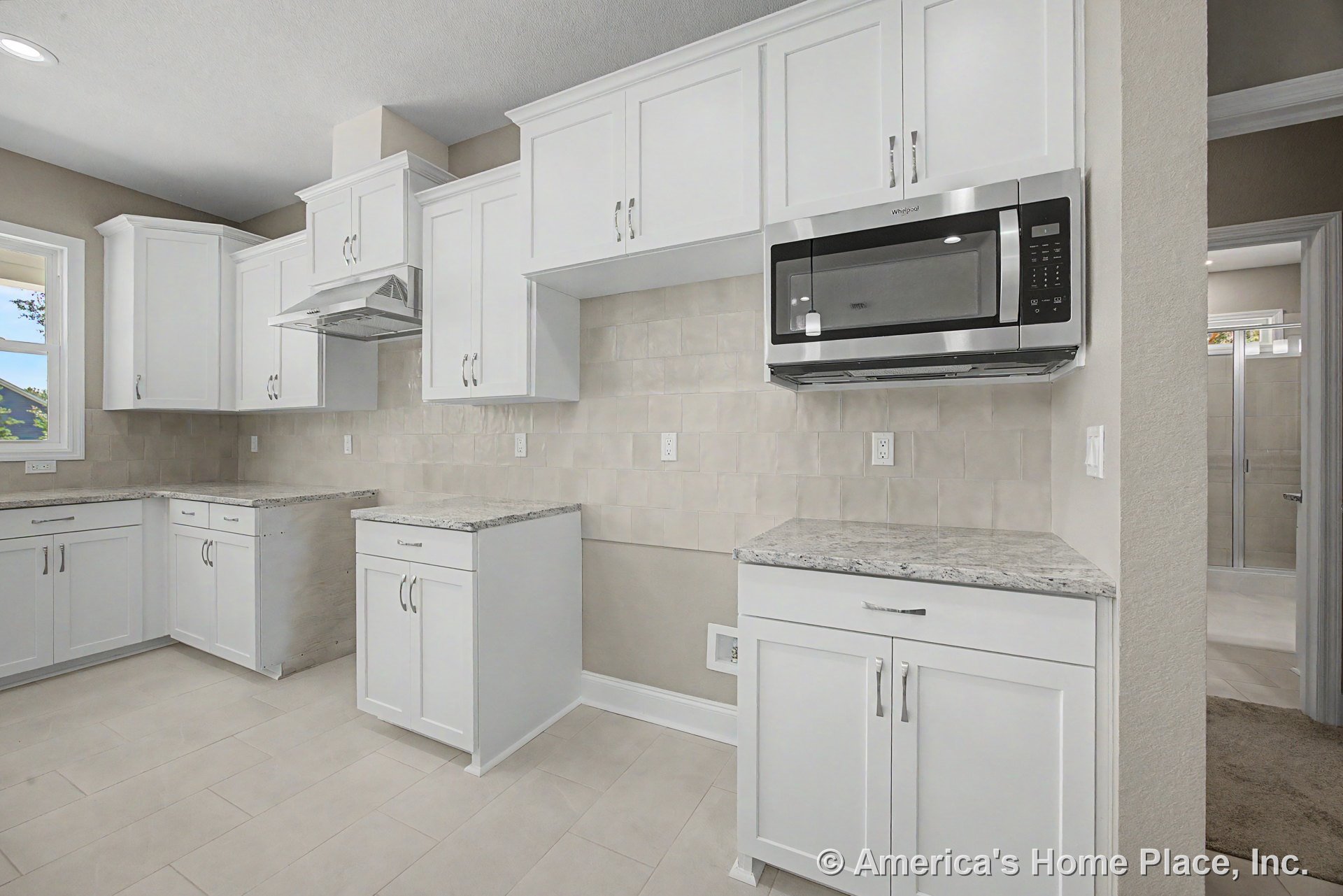 White shaker cabinets with granite countertops, built-in stainless steel microwave, neutral tile backsplash, tile flooring, vent hood above range area, recessed lighting, window