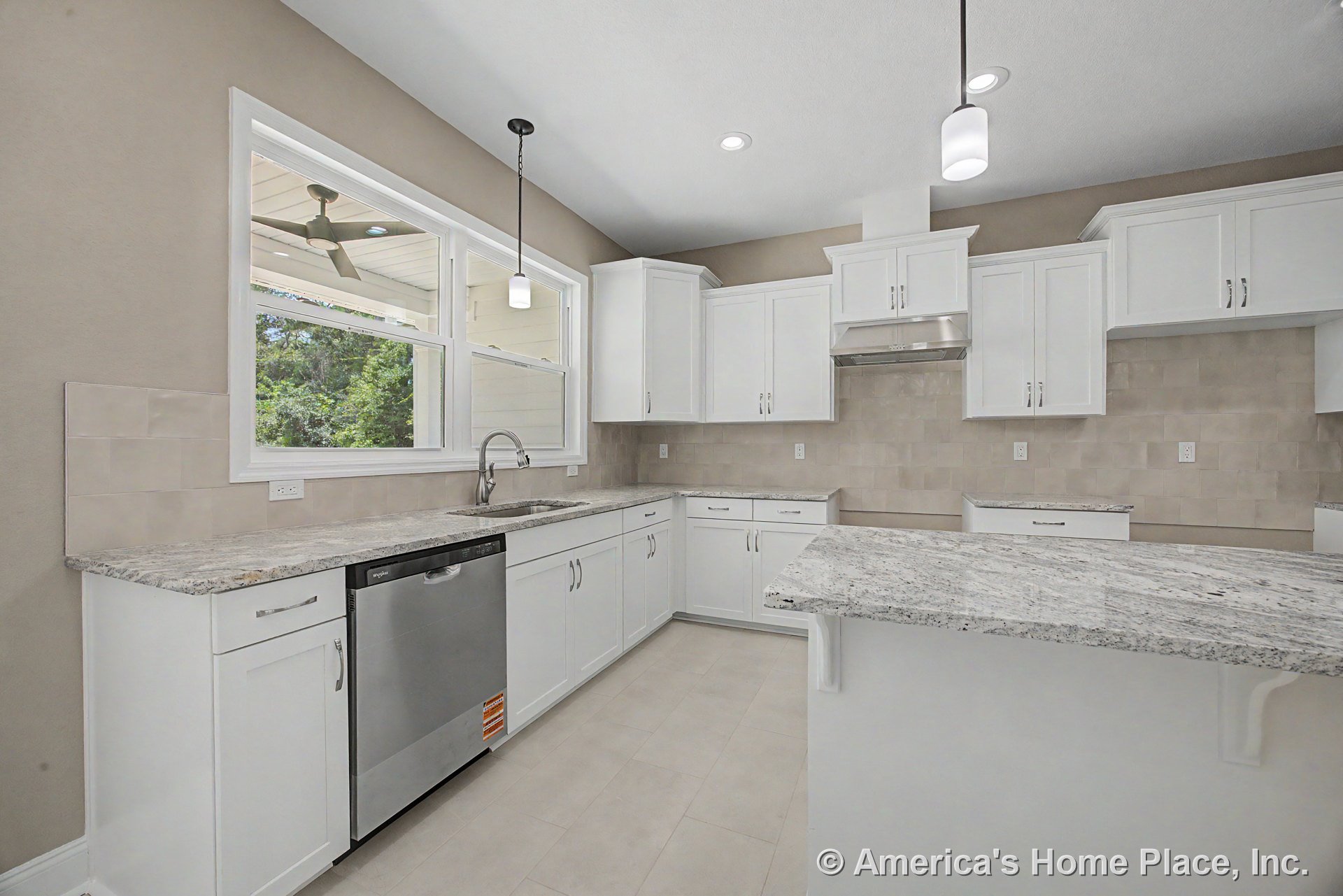 White shaker cabinets and neutral tile backsplash surround a granite peninsula countertop; large double window above the sink, stainless steel dishwasher, pendant and recessed
