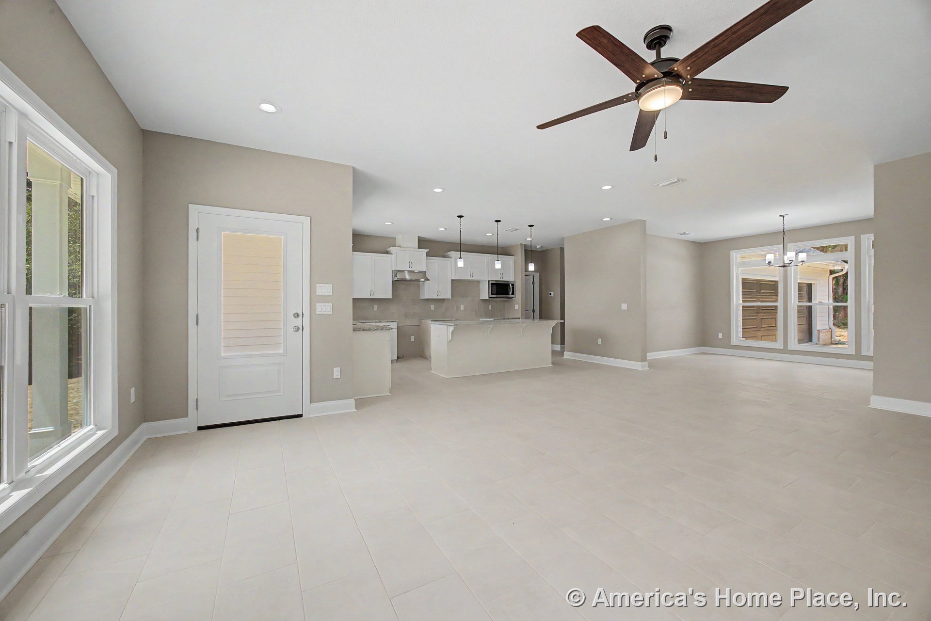 Open concept living area with tile flooring, recessed lighting, ceiling fan, and large windows; kitchen features white cabinetry, granite countertops, and pendant lights above the