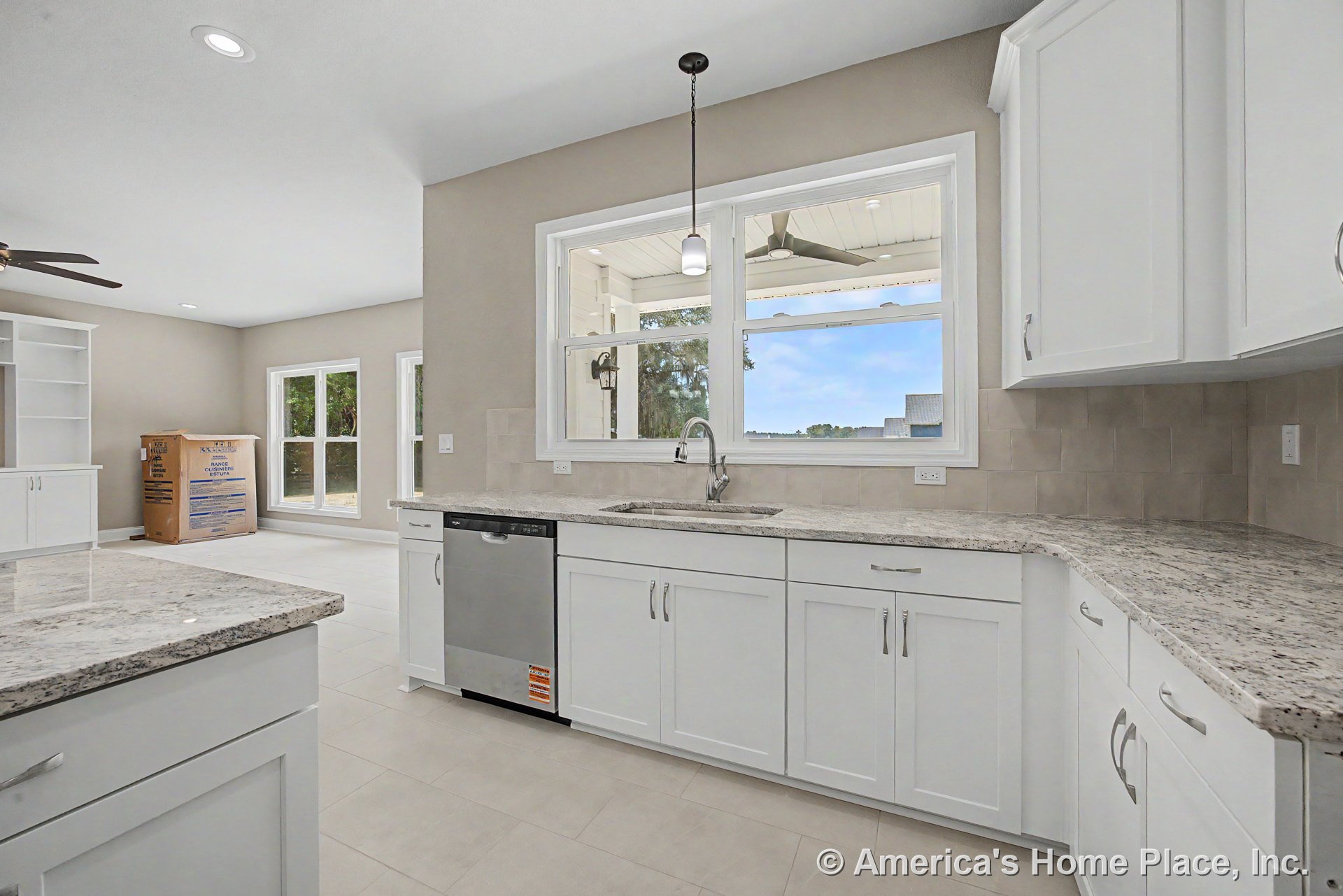 White shaker cabinets with granite countertops, tile backsplash, stainless steel dishwasher, undermount sink, pendant light fixture, and a large double window overlooking a covered