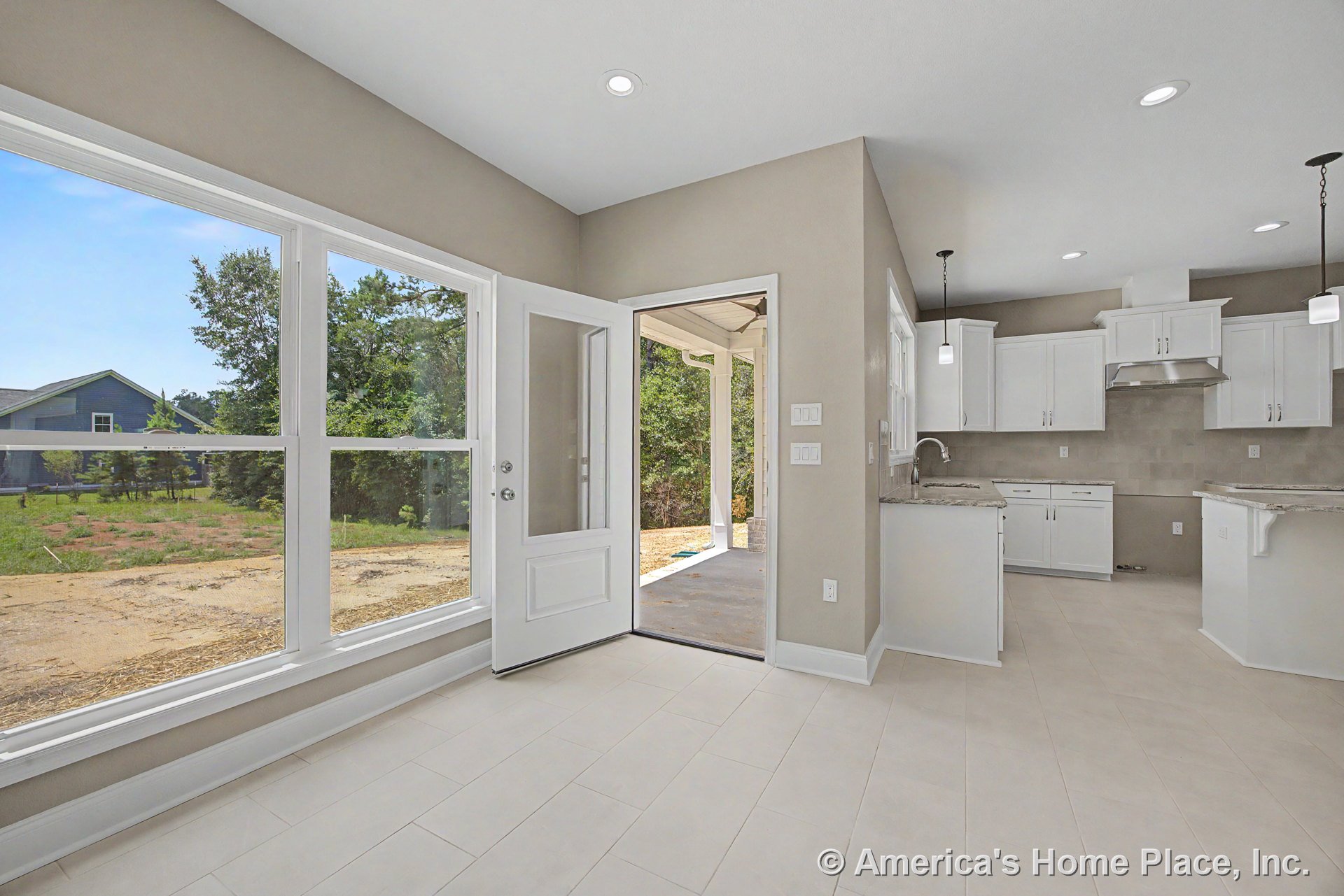 Kitchen and dining area with large windows, white shaker cabinets, granite countertops, tile flooring, pendant and recessed lighting, open patio door, neutral walls, and trim in an