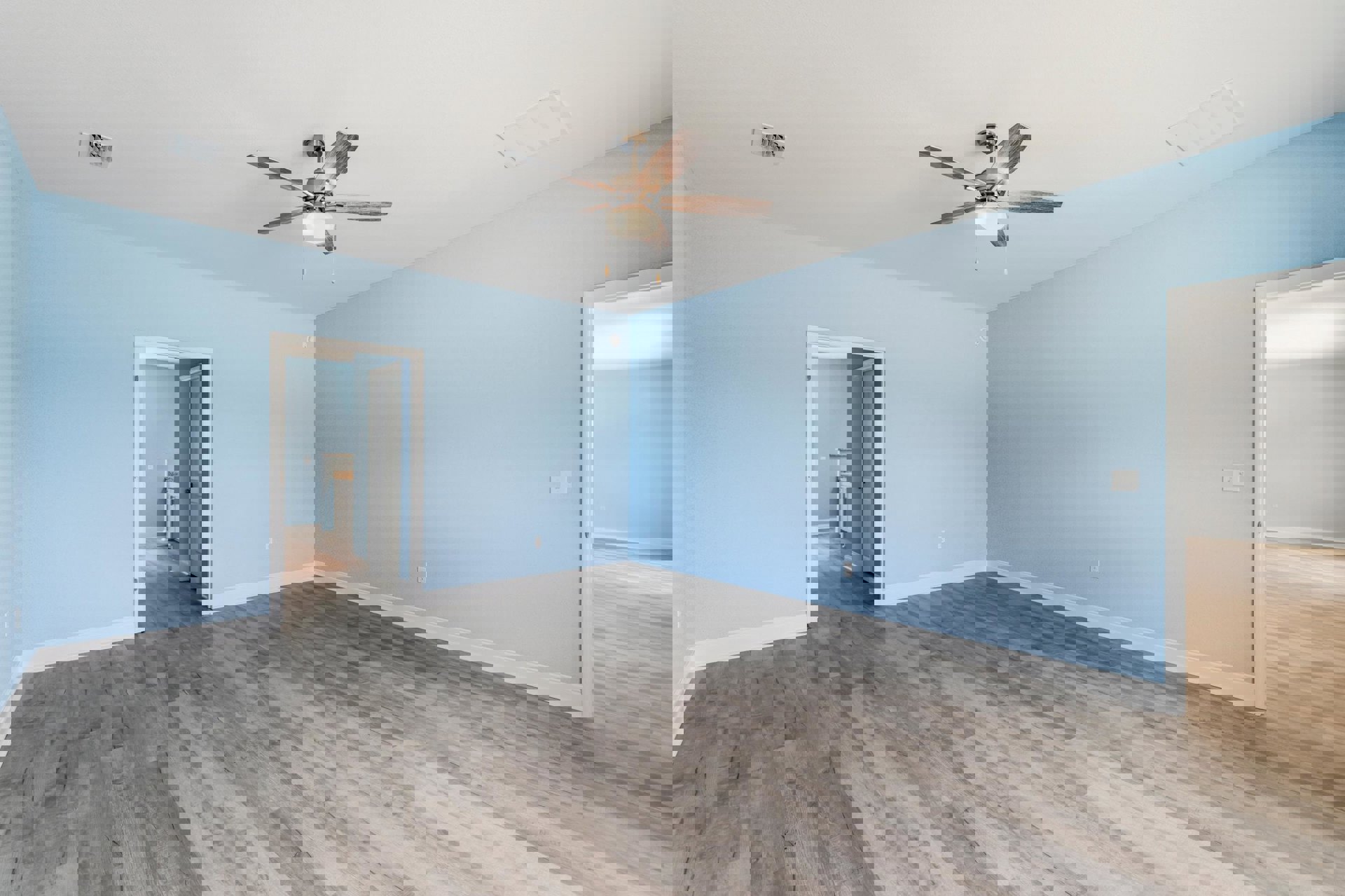 Ceiling fan with light fixture mounted on white ceiling, wood laminate flooring, plaster walls, wall vent visible in residential interior room