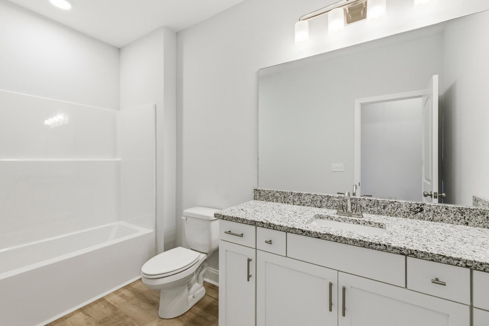 Bathroom with marble countertop, white bathtub, white toilet, tile flooring, and white door with matching frame