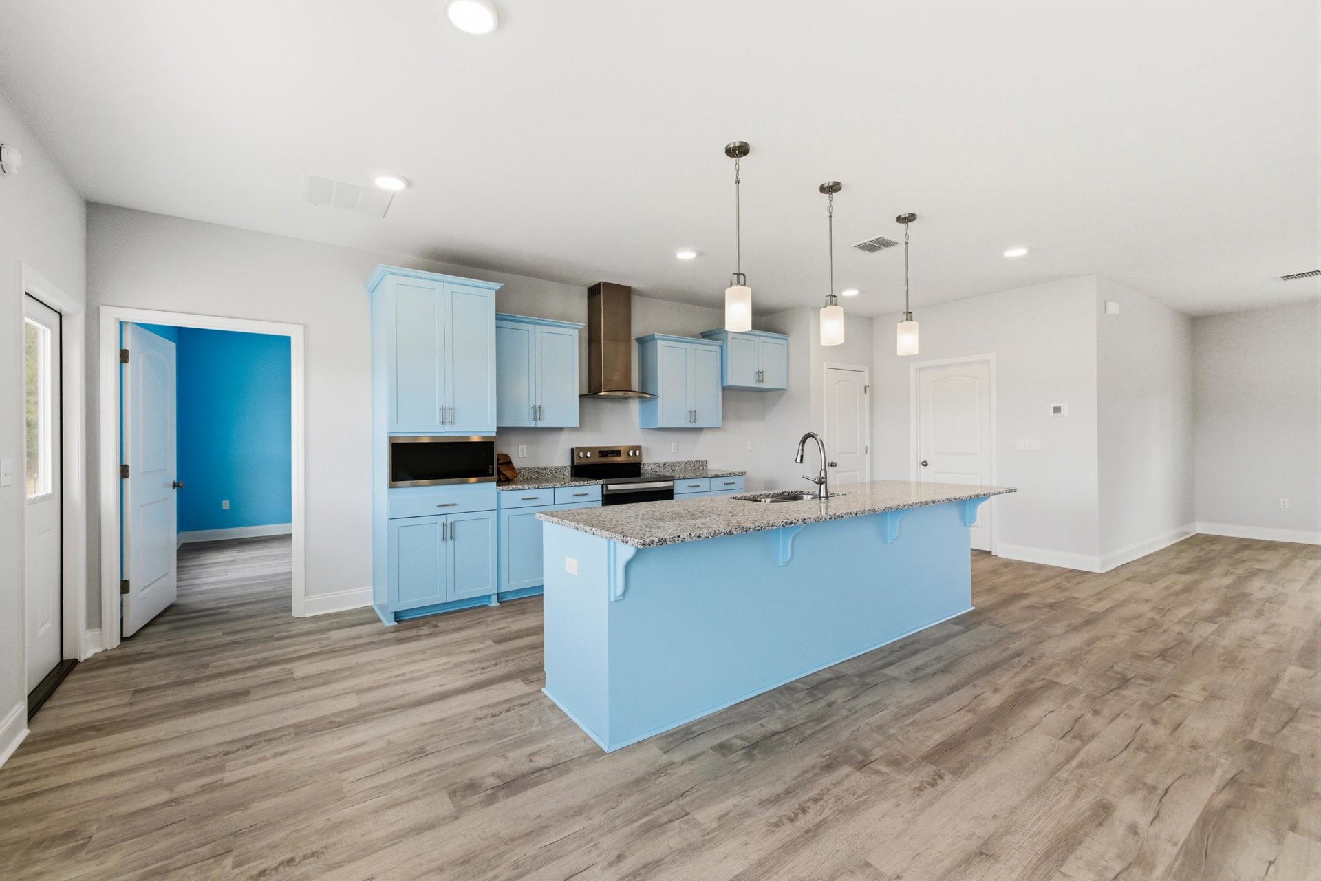 Marble countertop kitchen with wood flooring, white cabinetry, stainless steel sink, and recessed lighting