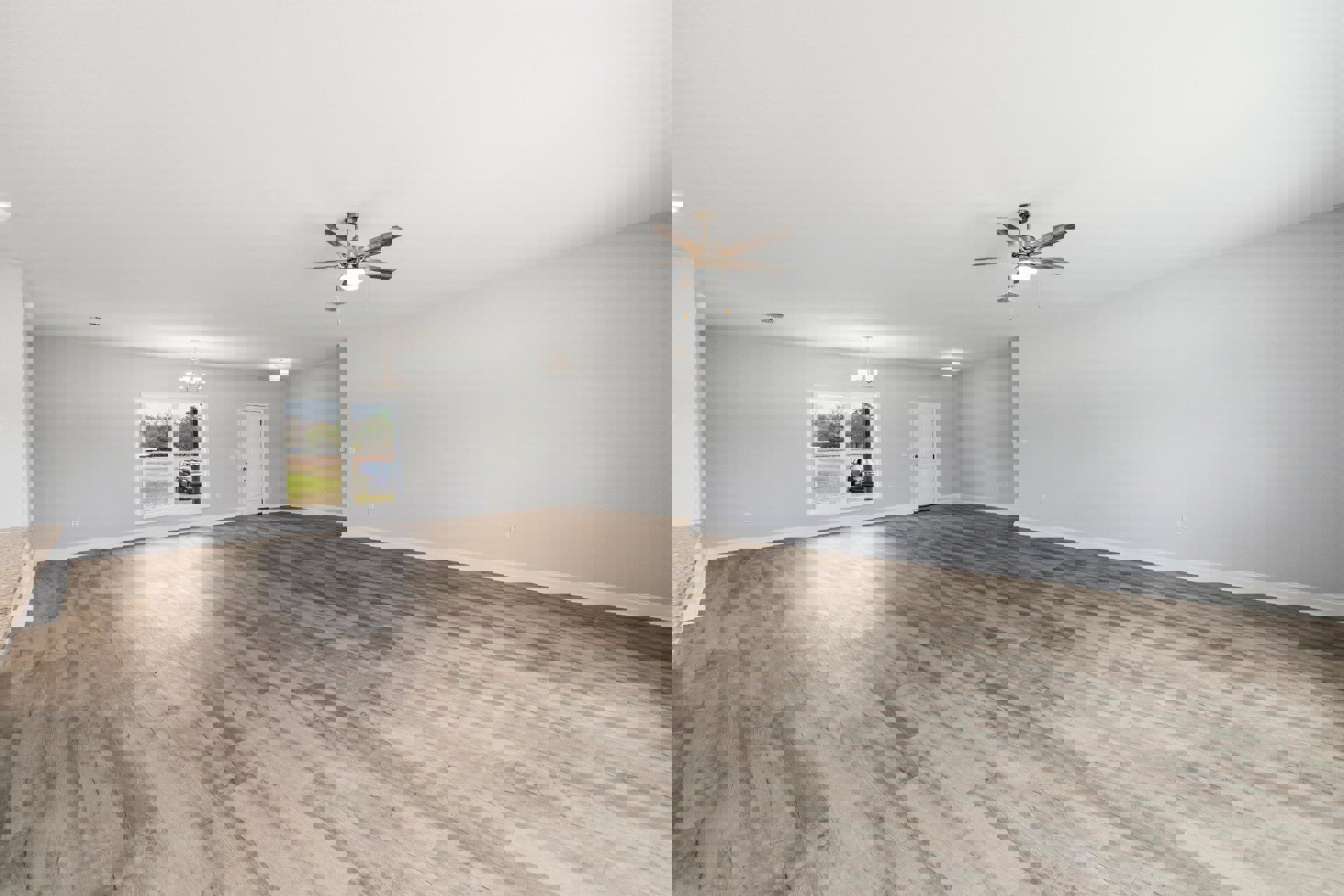 Spacious room with hardwood flooring, white walls, ceiling fan with light fixture, white door with black handle, large window overlooking parked car on grass