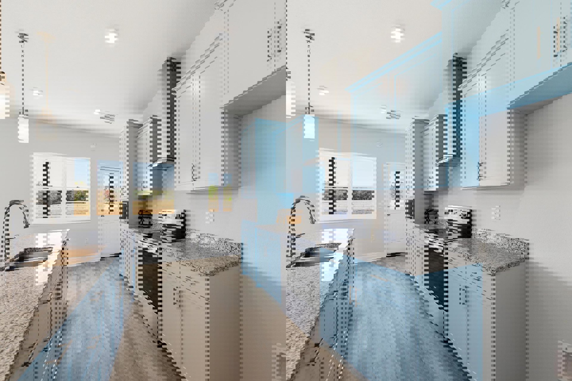 Blue kitchen cabinets with granite countertops, stainless steel sink, window overlooking a field, white door with glass panel, ceiling light fixture, metal pole with sign, close-up