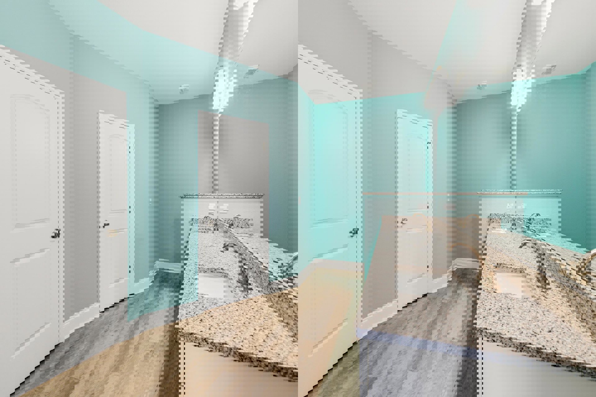 Bathroom with blue painted walls, white paneled door with silver knob, white porcelain sink and chrome faucet, wood flooring