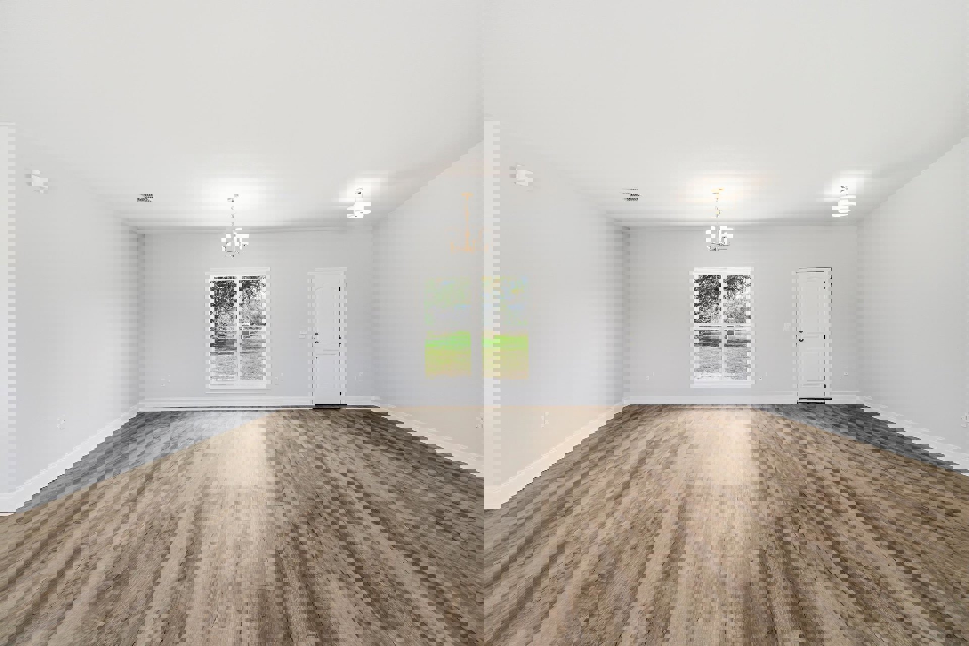 Wood floor room with white plaster walls, white door with silver handle, window overlooking grassy field, ceiling chandelier and recessed light.