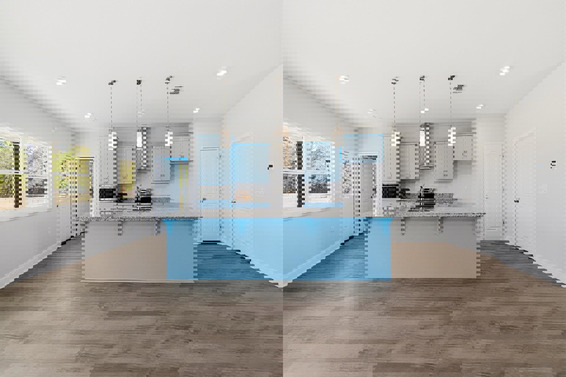 Blue kitchen island with white countertop and built-in sink, wood flooring, blue accent wall, rectangular window with black frame, white door with silver knob, cabinetry, and