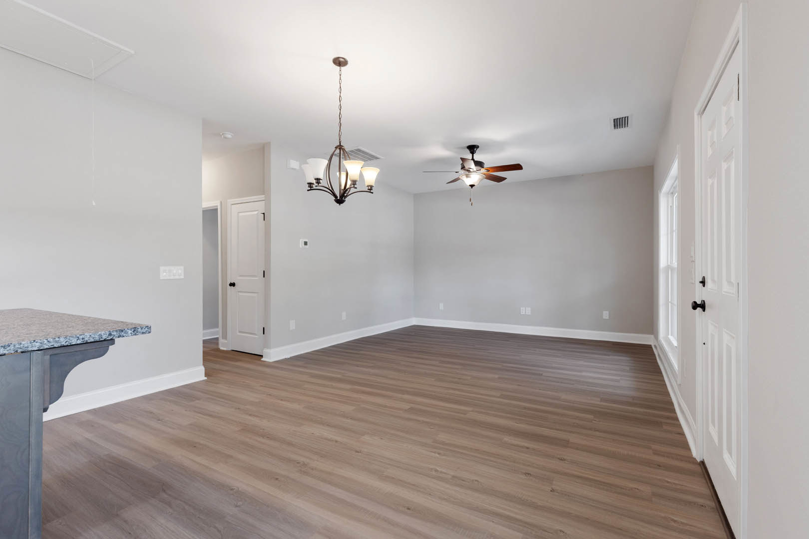 Hardwood floor with marble-topped cabinet, white walls, ceiling fan with light, white door featuring black knobs