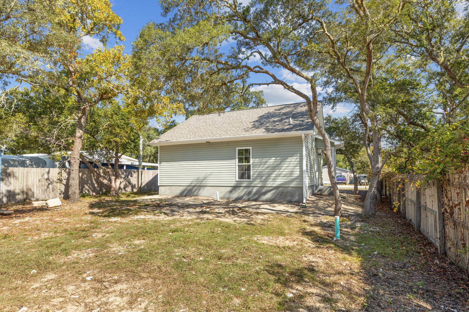 Two-story custom home with white-framed windows, gray roof, surrounded by mature trees and a grassy lawn