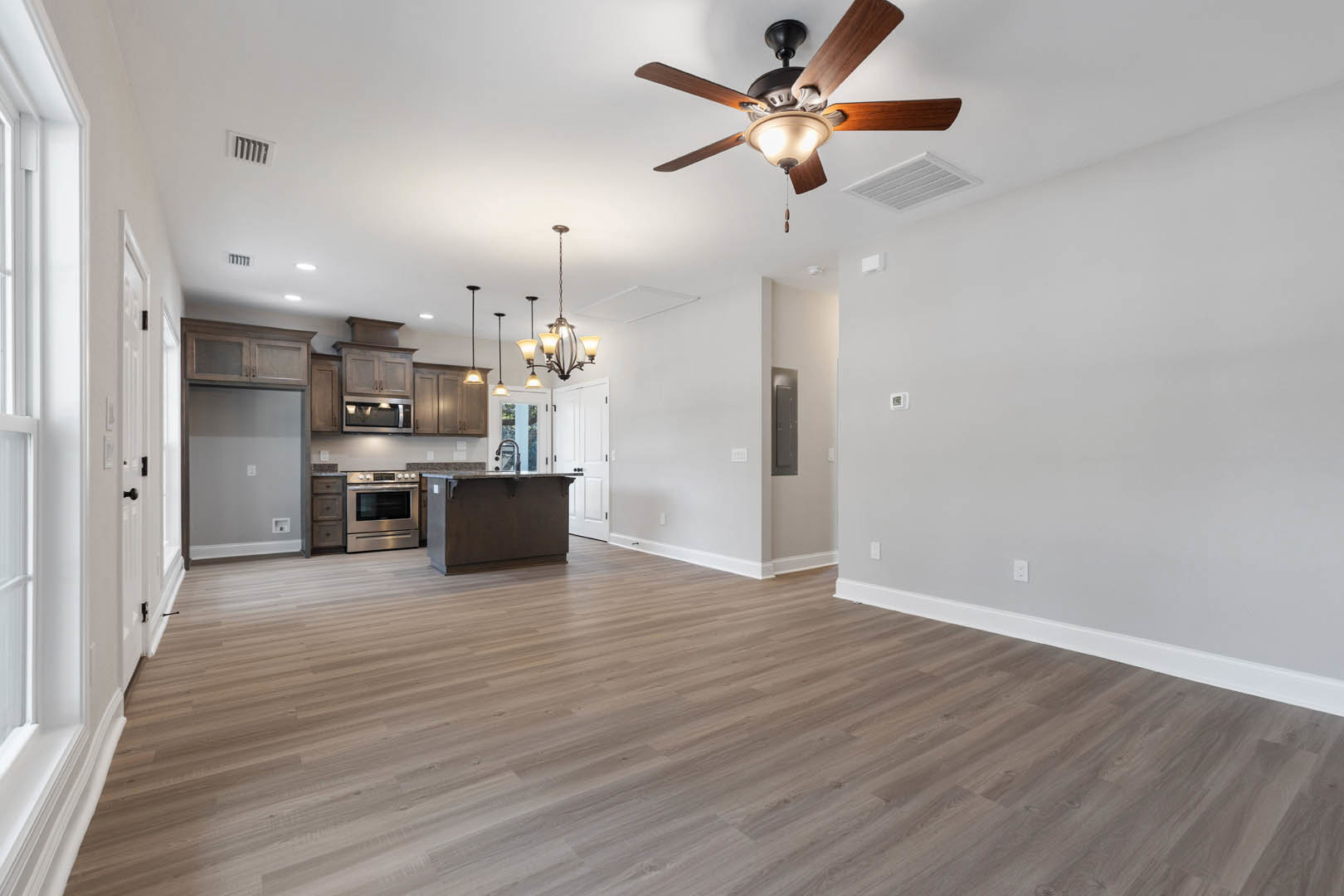 Ceiling fan with integrated light fixture mounted on white ceiling above wood flooring in a residential room