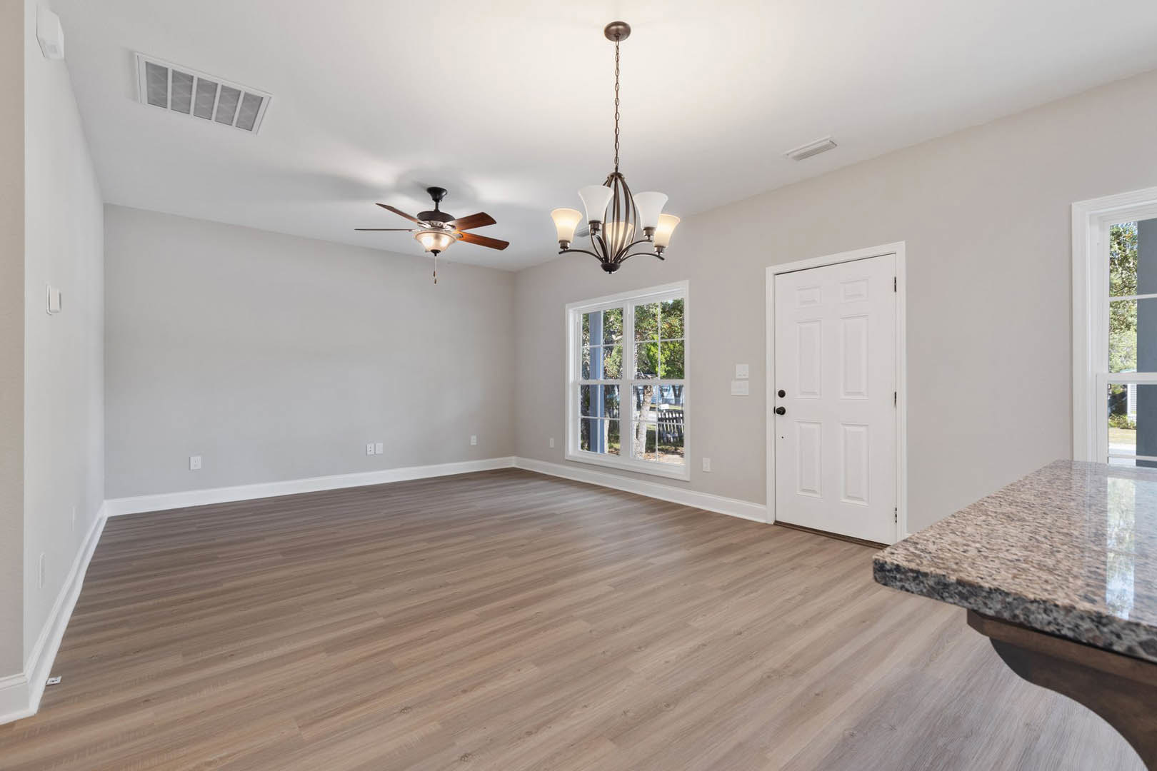 Ceiling fan with light fixture, multi-pane window, white door with black knobs, hardwood floor, white walls