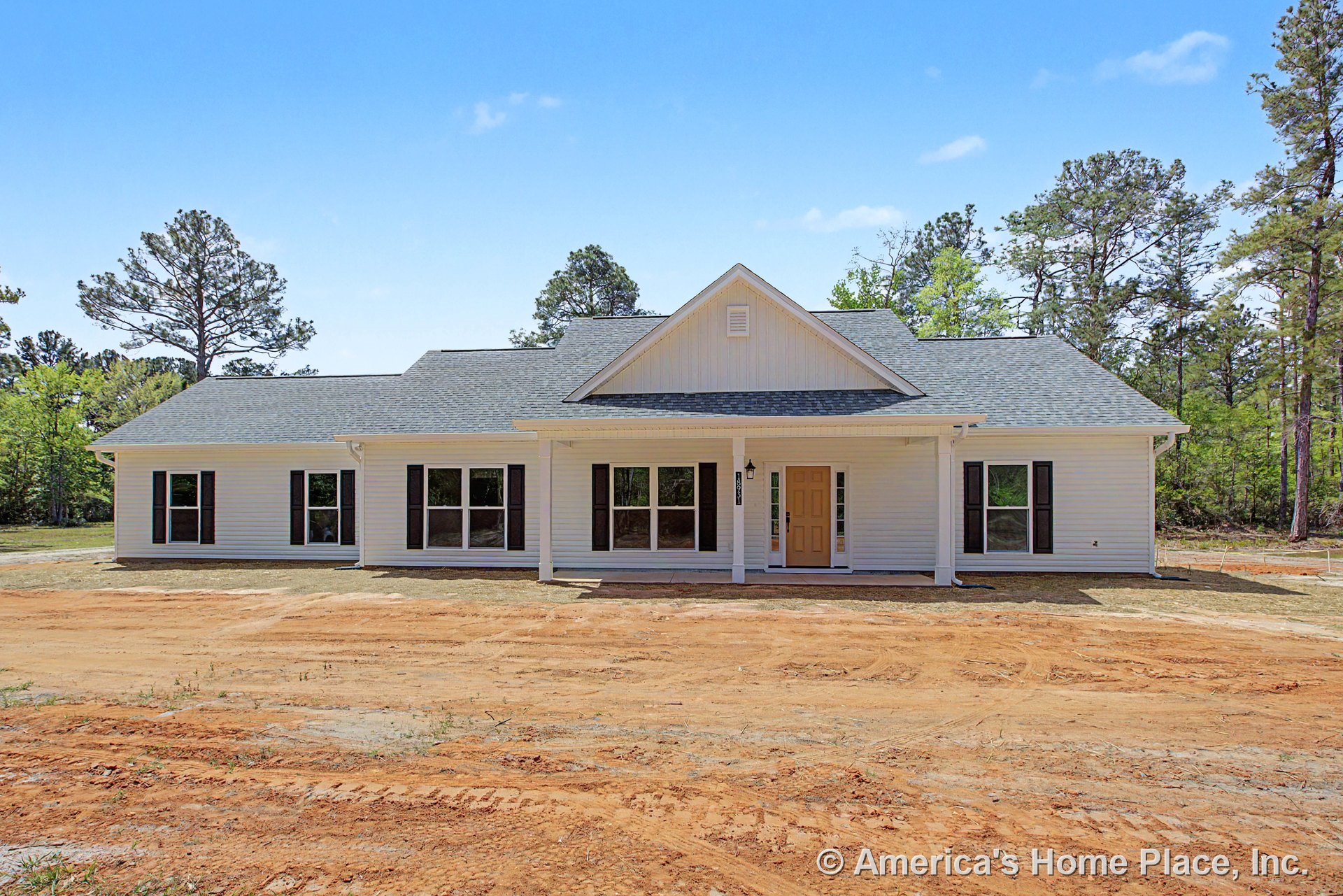 Covered front porch with gable roof, light-colored siding, multiple large windows with black shutters, front entry door featuring sidelights, and decorative trim.