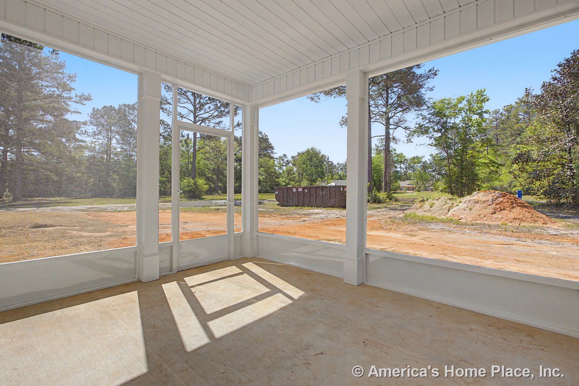 Screened-in porch with white painted trim, concrete flooring, paneled ceiling, vertical support posts, exterior door, and windows.