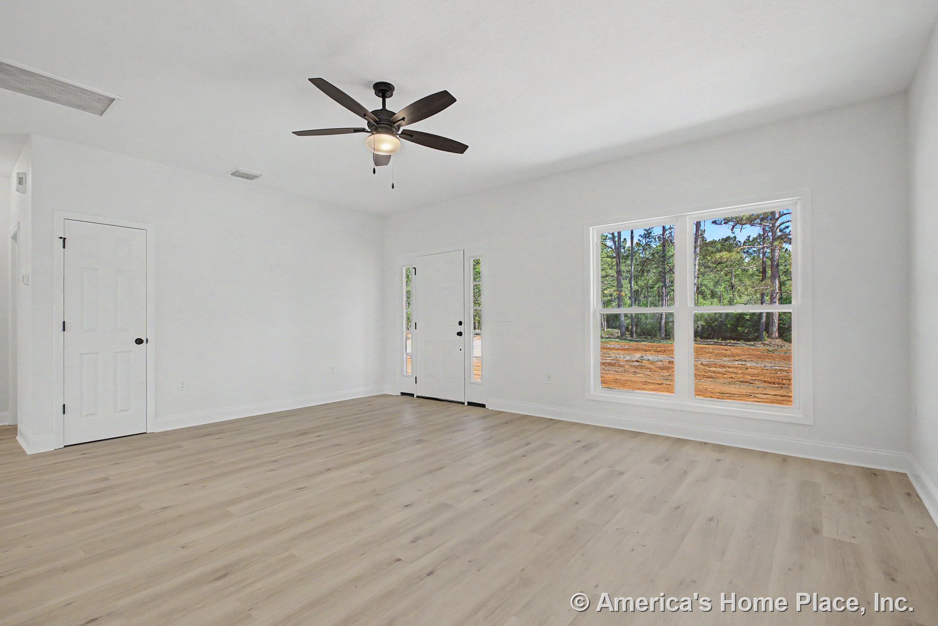 Light wood plank flooring, white trim and baseboards, large double window providing natural light, ceiling fan with integrated light, white interior and entry doors, neutral wall