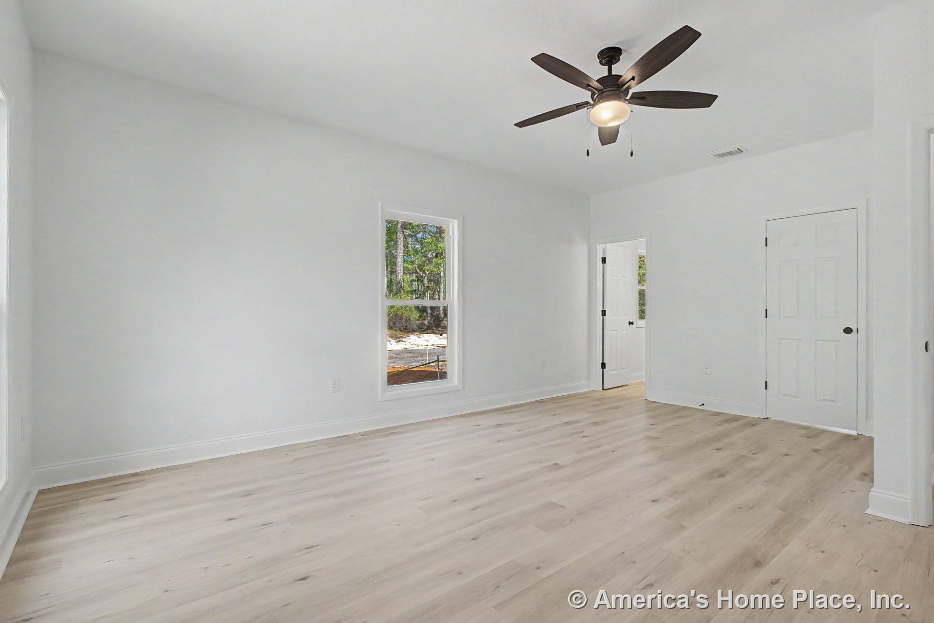 Bedroom with light wood plank flooring, white walls and trim, double-hung windows allowing natural light, ceiling fan with integrated lighting, white paneled doors, and a smooth