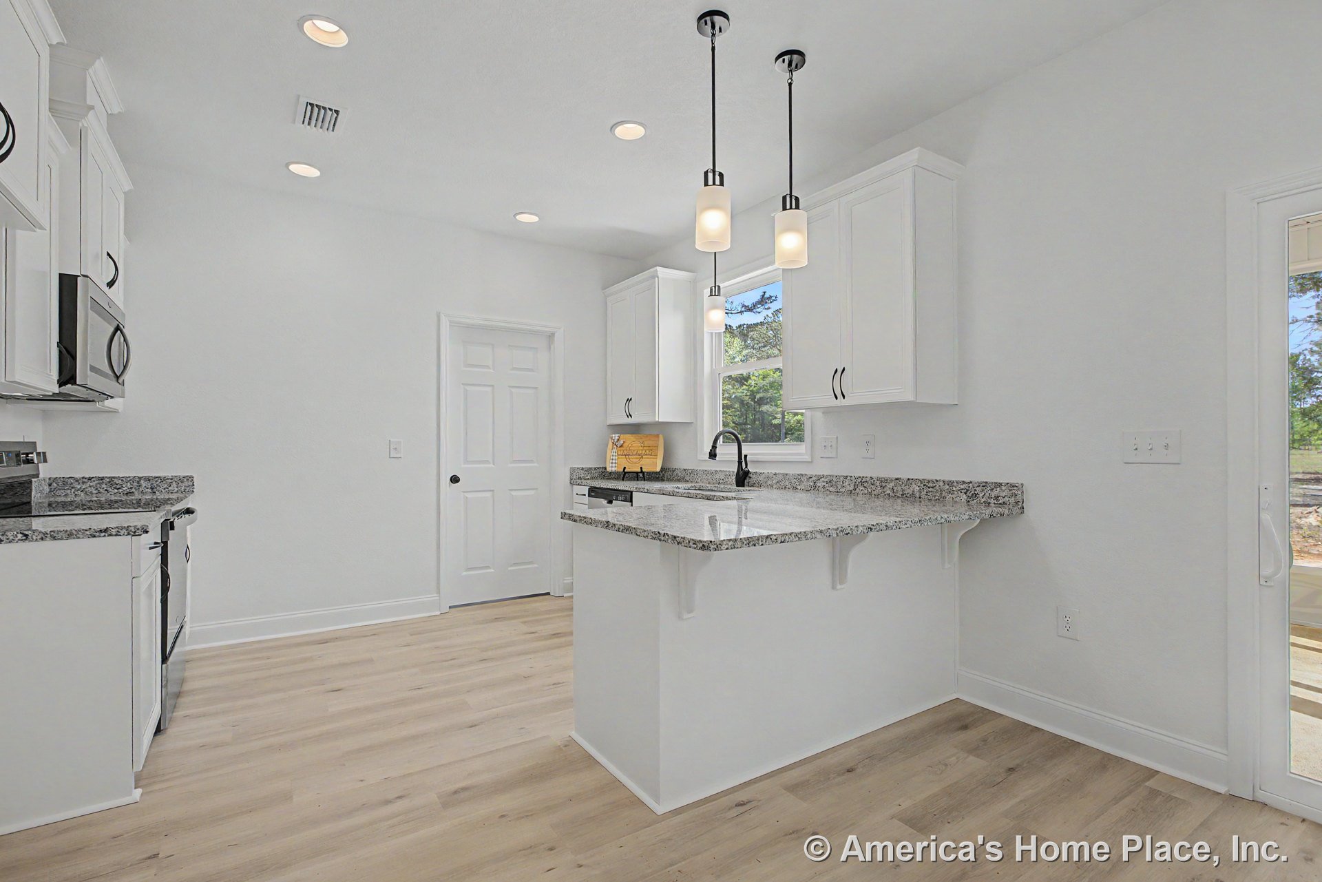 White upper and lower cabinets with granite countertops, pendant lights above the peninsula, light wood flooring, window above built-in sink, recessed ceiling lights, stainless