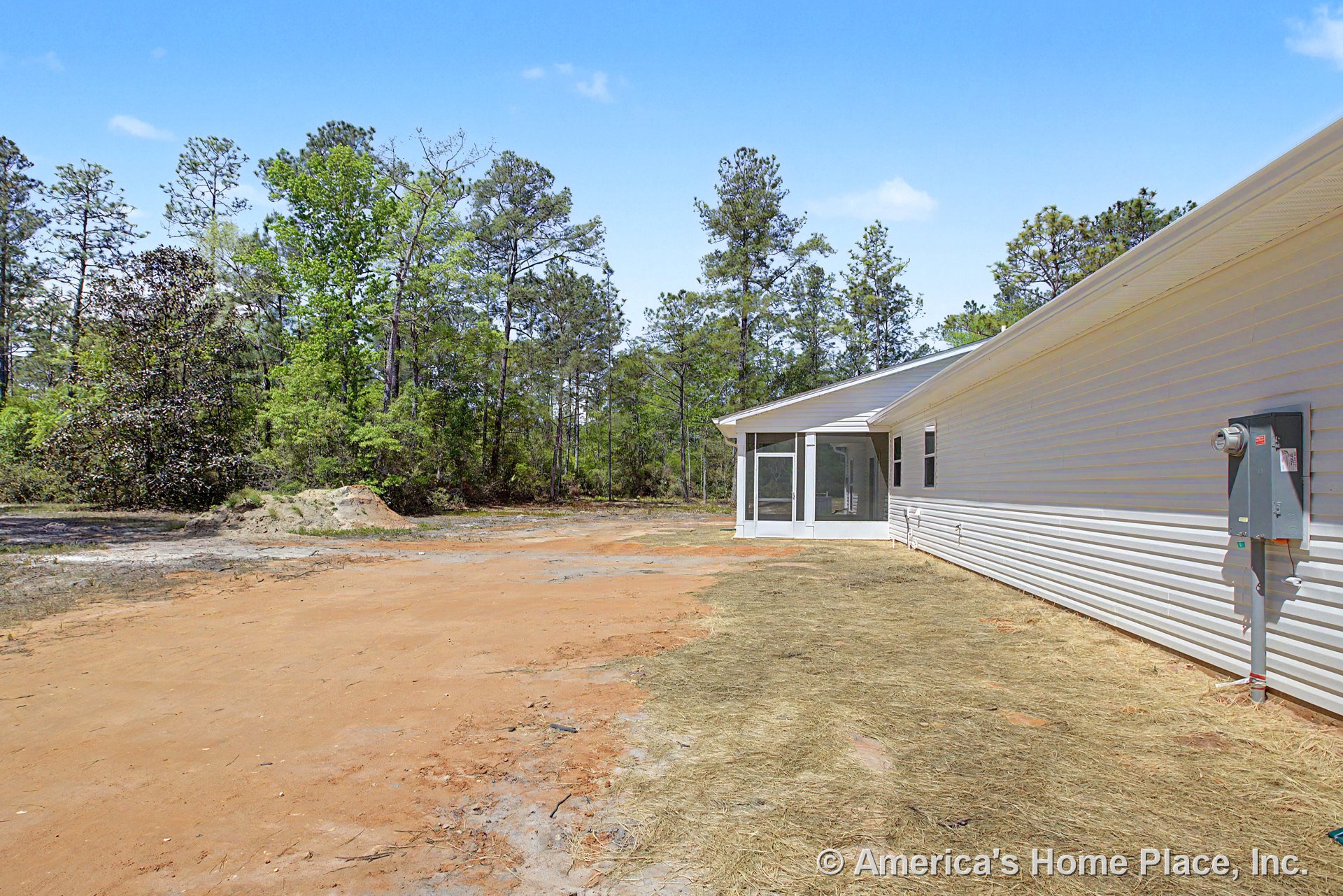 White vinyl siding exterior with multiple windows, screened rear porch enclosure, sloped roofline, utility meter box, and unfinished yard.