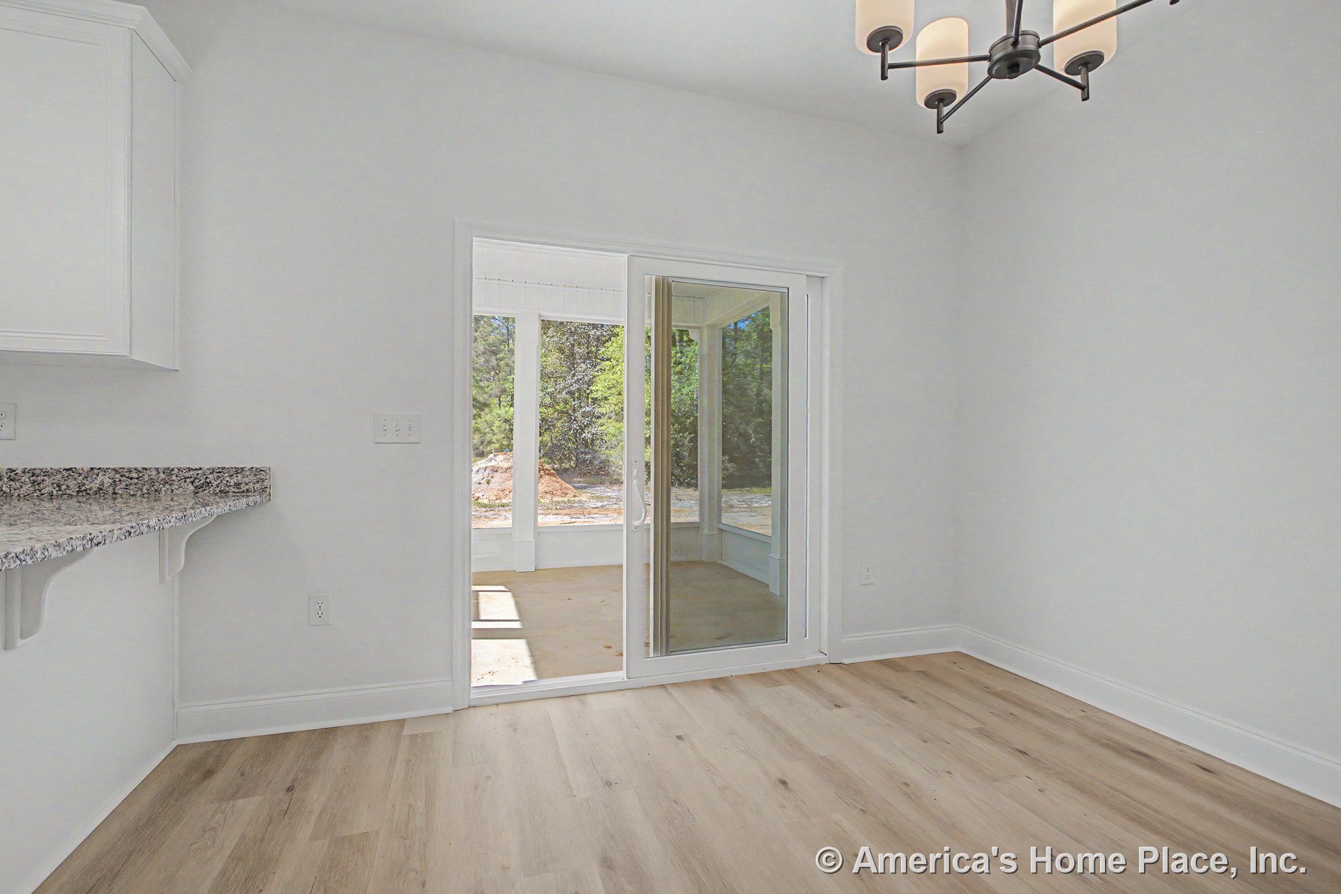 Dining area with light wood plank flooring, granite breakfast bar, white cabinetry, modern chandelier, sliding glass patio door opening to covered porch, neutral walls, and open