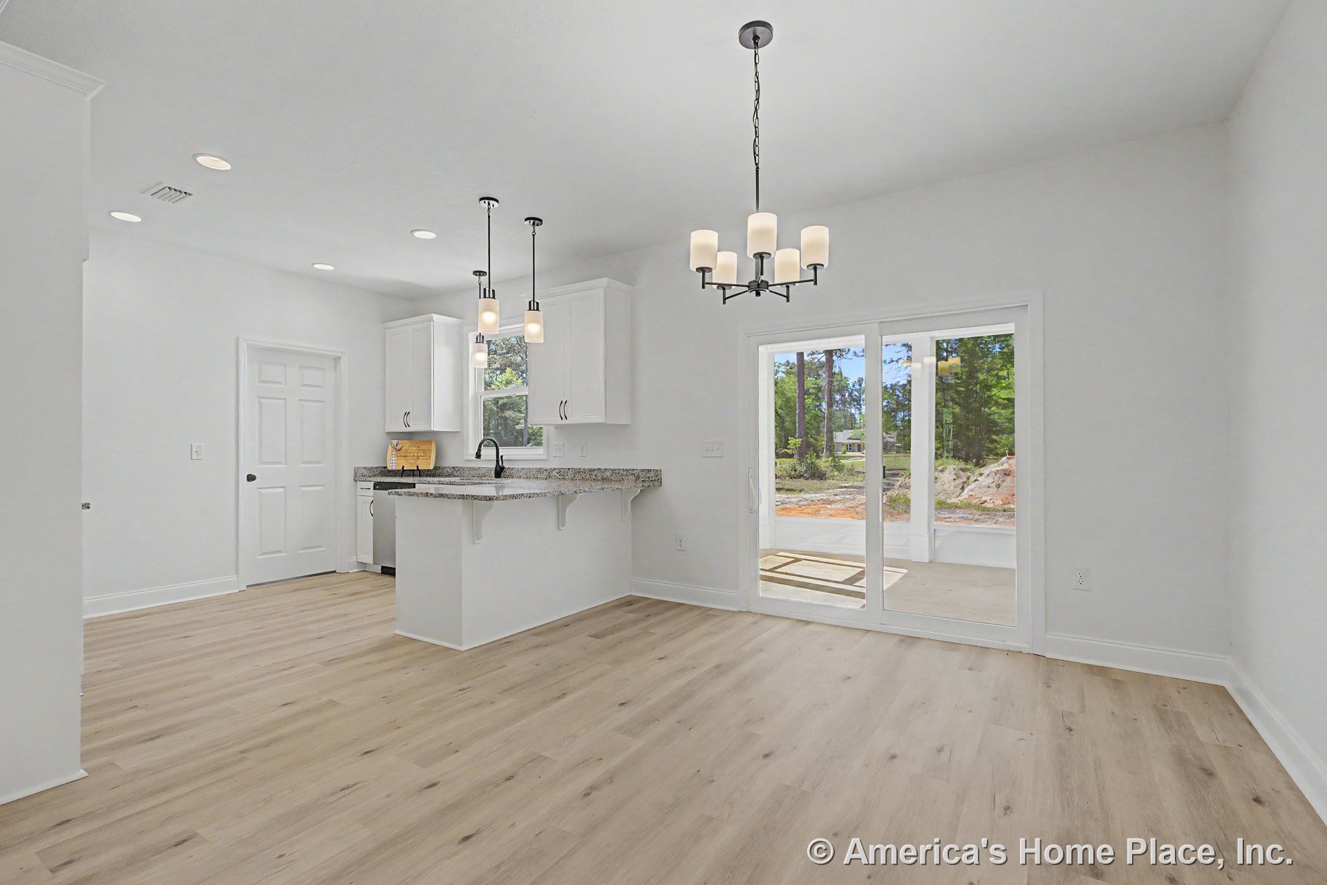 Open kitchen and dining area with white cabinetry, granite breakfast bar, pendant lights above island, chandelier over dining table, light wood flooring, recessed lighting, and