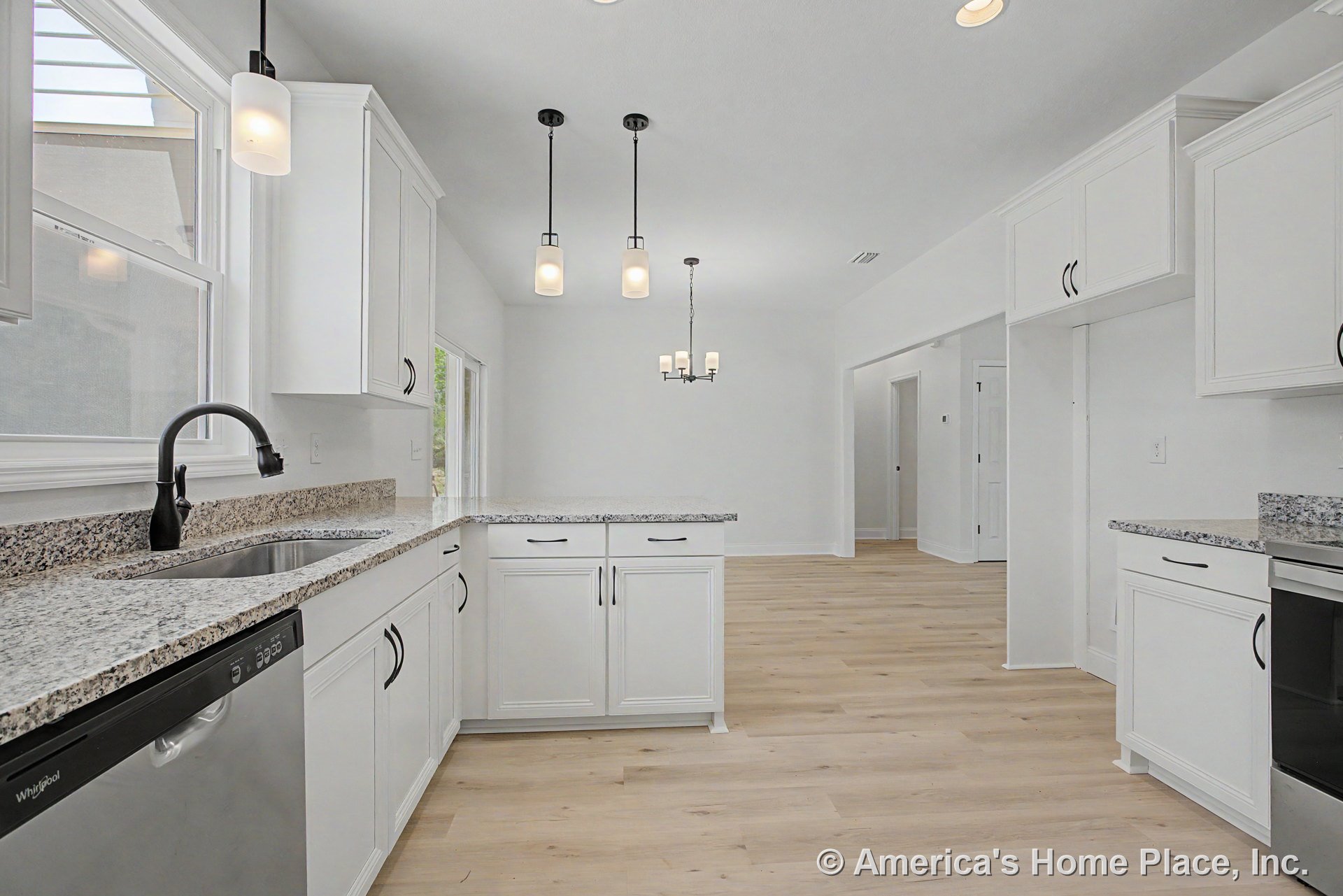 White upper and lower kitchen cabinets with granite countertops, black faucet and hardware, stainless steel dishwasher, pendant lights above the island, open layout connecting to