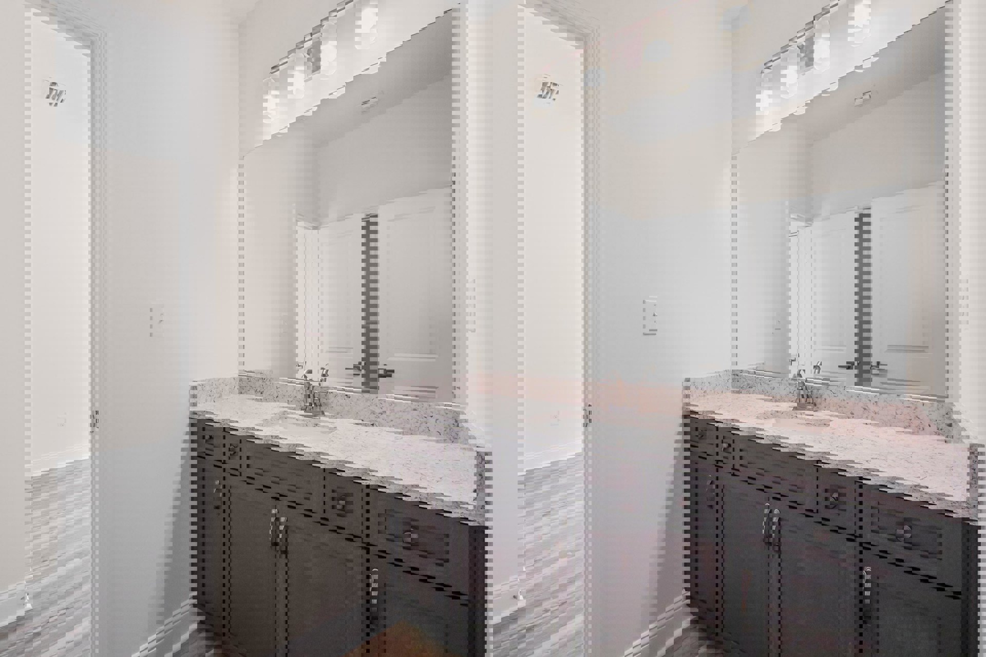 Modern bathroom featuring a rectangular mirror above a white sink with chrome faucet, light-colored tile backsplash, white cabinetry with drawers, and a white door set in a smooth