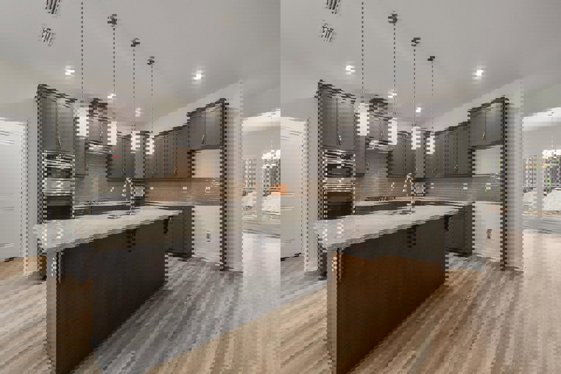 Kitchen with large central island, wood flooring, white cabinetry, stainless steel microwave, undermount sink, and white door with silver handle