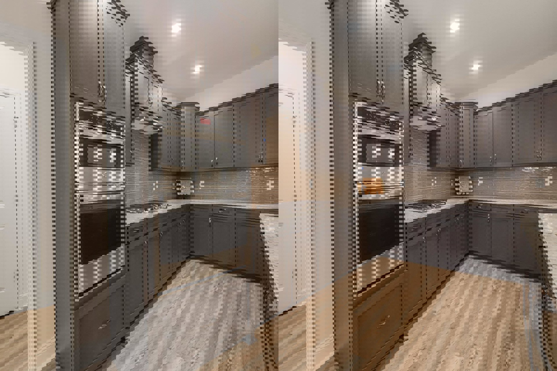 Dark wood kitchen cabinets, stainless steel oven with glass door, built-in microwave, light fixture on ceiling, stone countertops, hardwood flooring