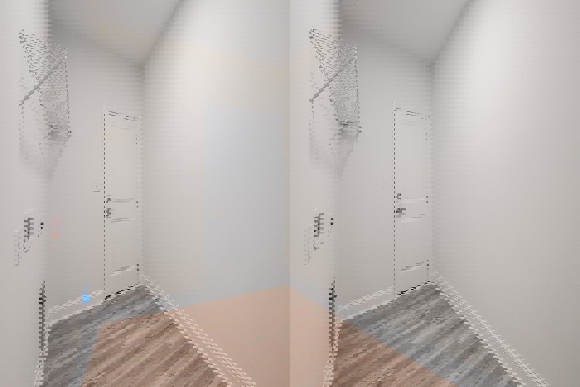 White door with silver handle and metal hinge set in a plaster wall, wood laminate flooring with white baseboard, white drying rack mounted on wall, close-up of water meter