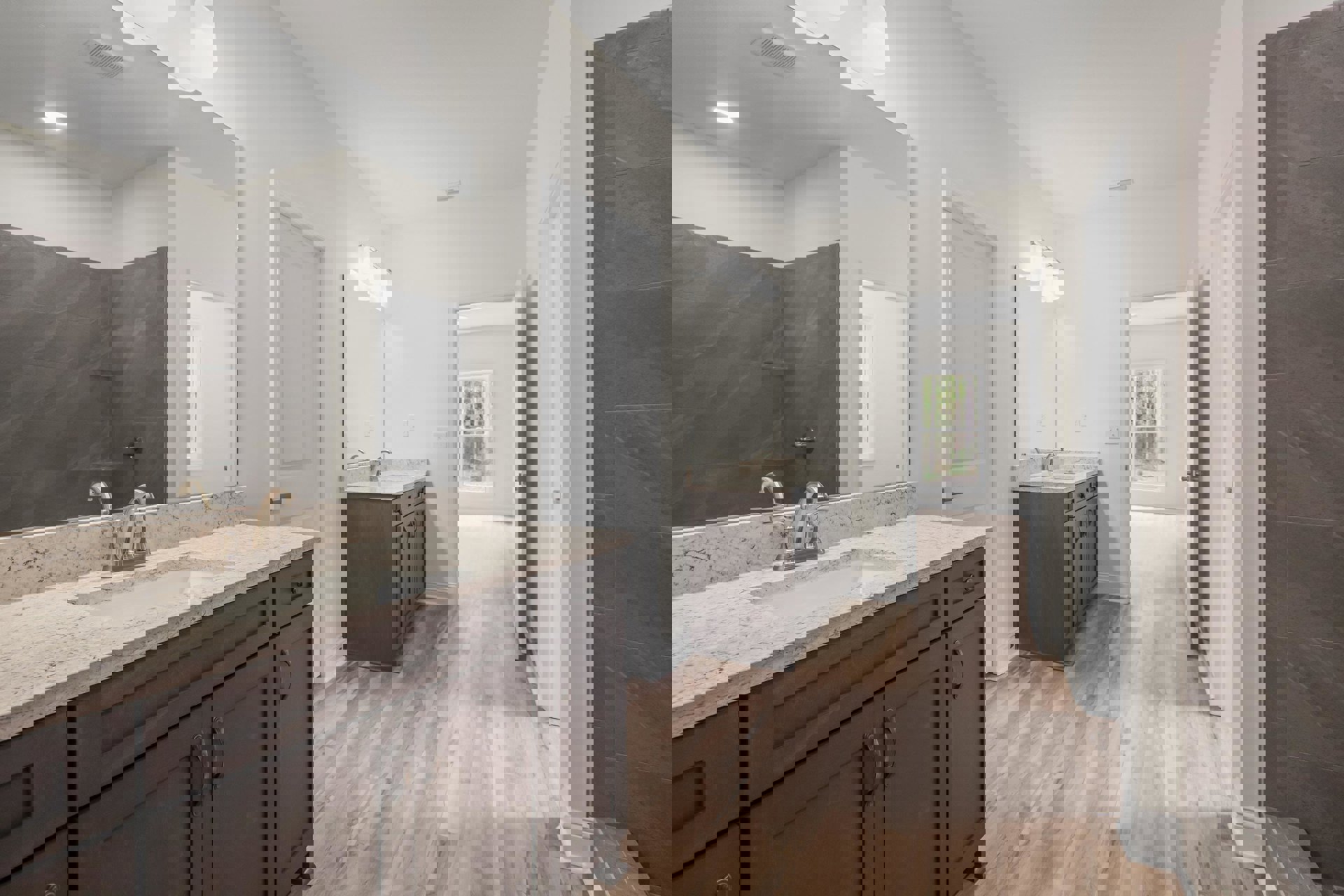 Bathroom with wood flooring, white walls, window, white door, built-in sink, and cabinetry with stone countertop