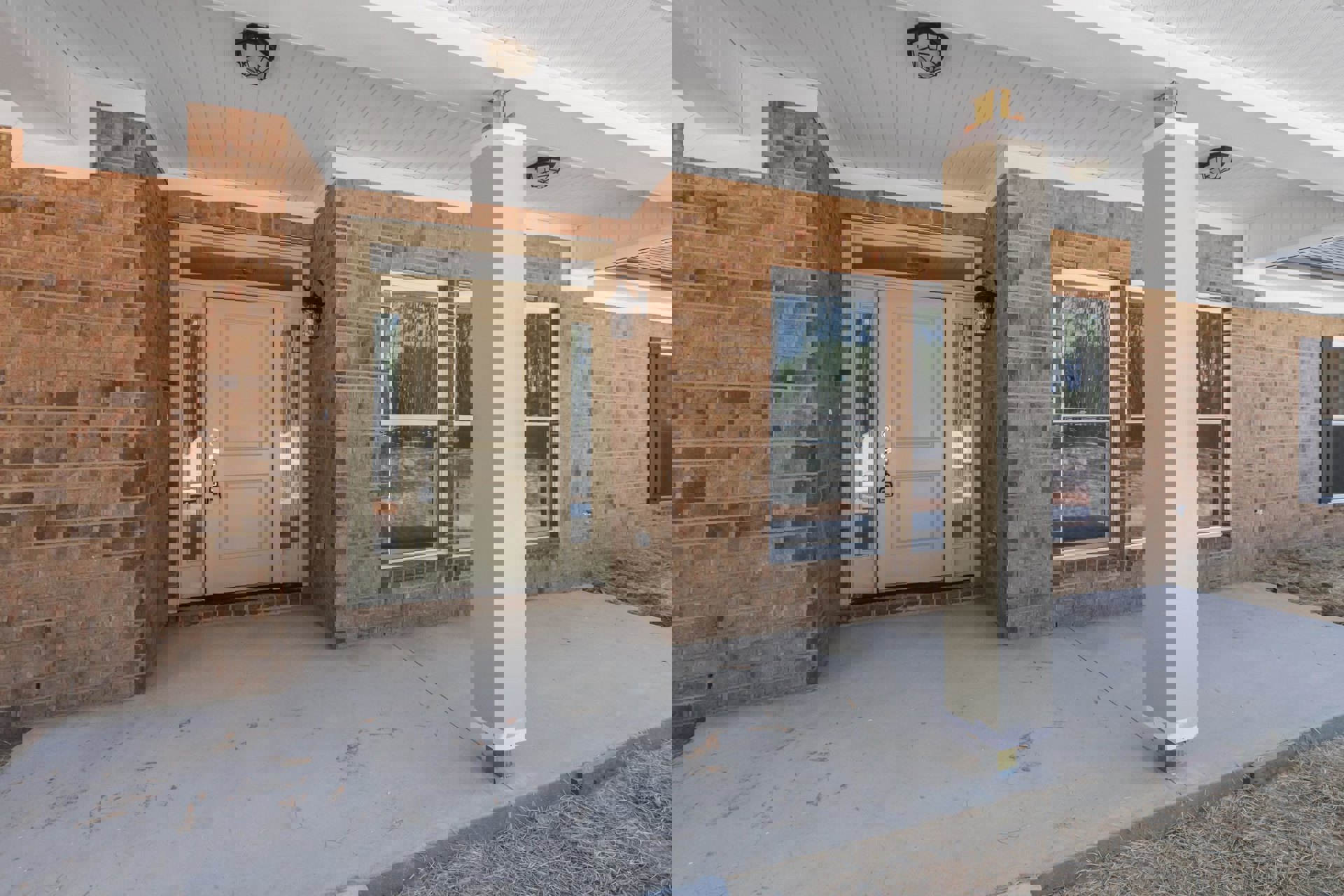 Brick house front porch with white plank ceiling, ceiling light fixture, white door featuring lock and handle, window showing trees outside