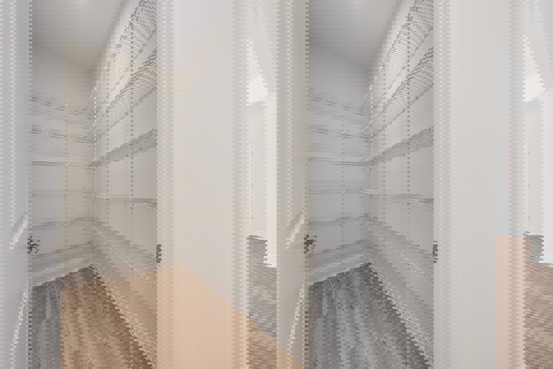 Empty closet with built-in white shelves, natural wood flooring, and white plaster walls