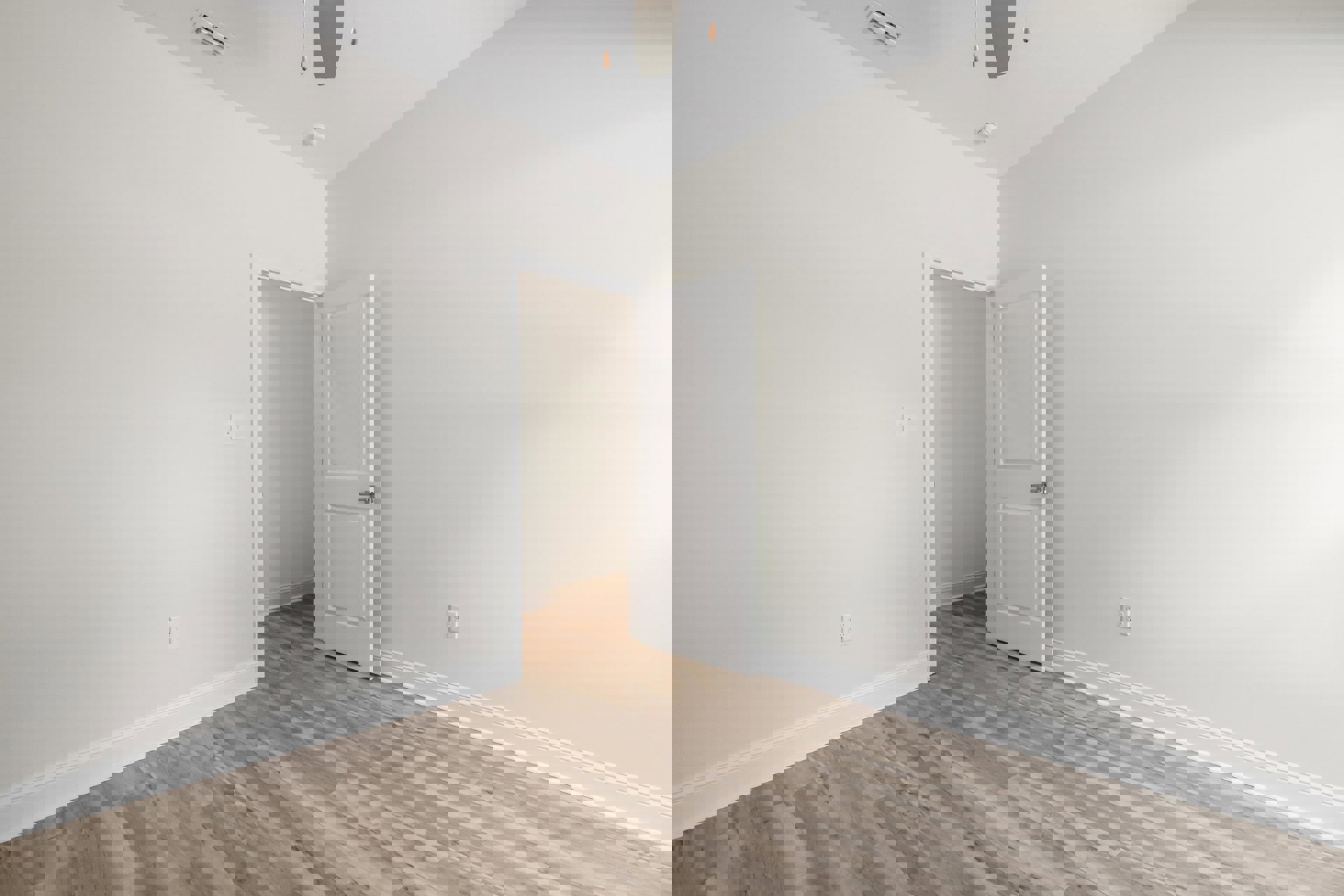 White door with silver handle set in a white wall with black border, wood laminate flooring, ceiling vent visible