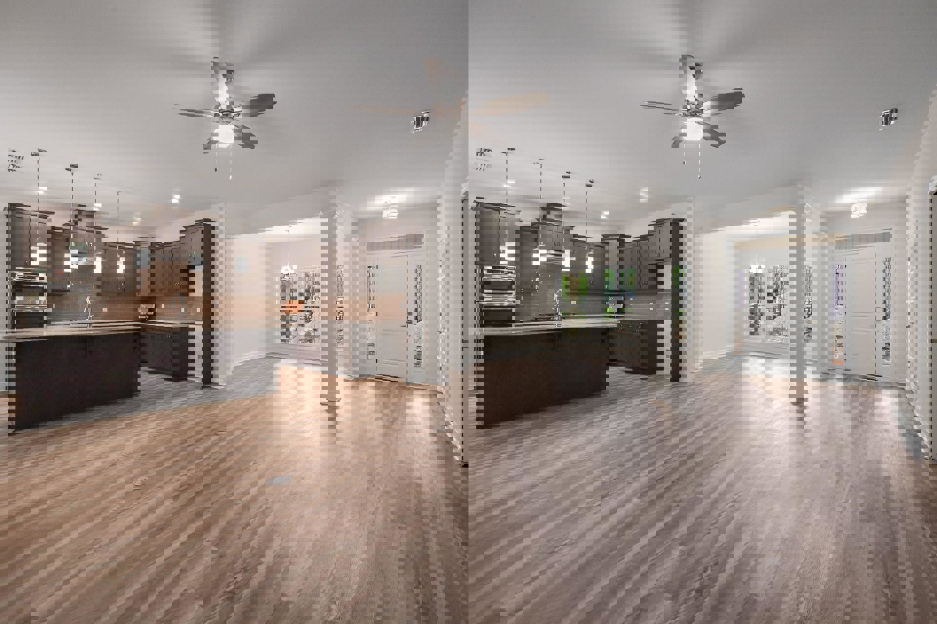 Spacious open floor plan featuring wood flooring, modern kitchen with stainless steel oven, white cabinetry, ceiling fan with light, and glass-paneled door leading to dining area