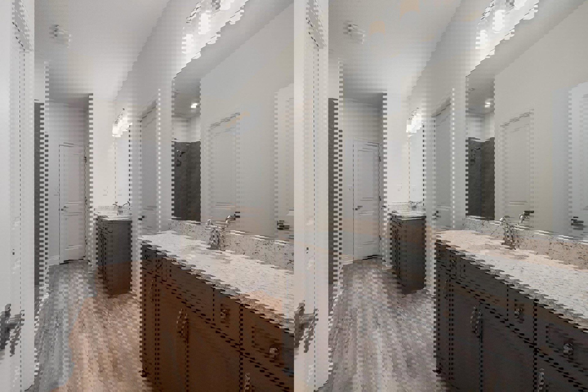 Bathroom with double vanity, rectangular mirrors above each sink, white cabinetry, wood flooring, and white door with silver handle