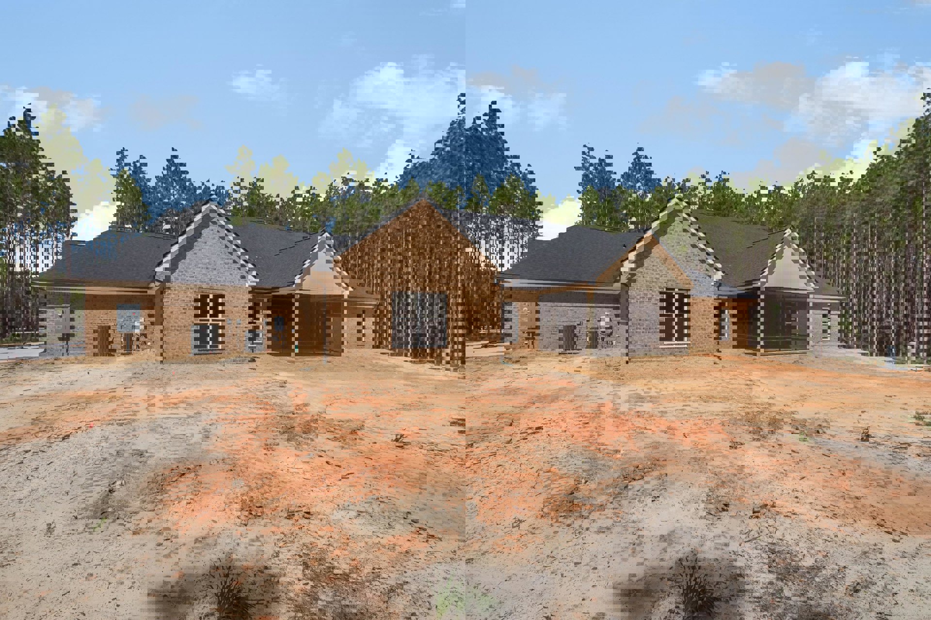 Modern home exterior with light-colored siding, large window, exposed utility meter, black metal box mounted on brick wall, dirt landscaping area, small plant, and roofline framed