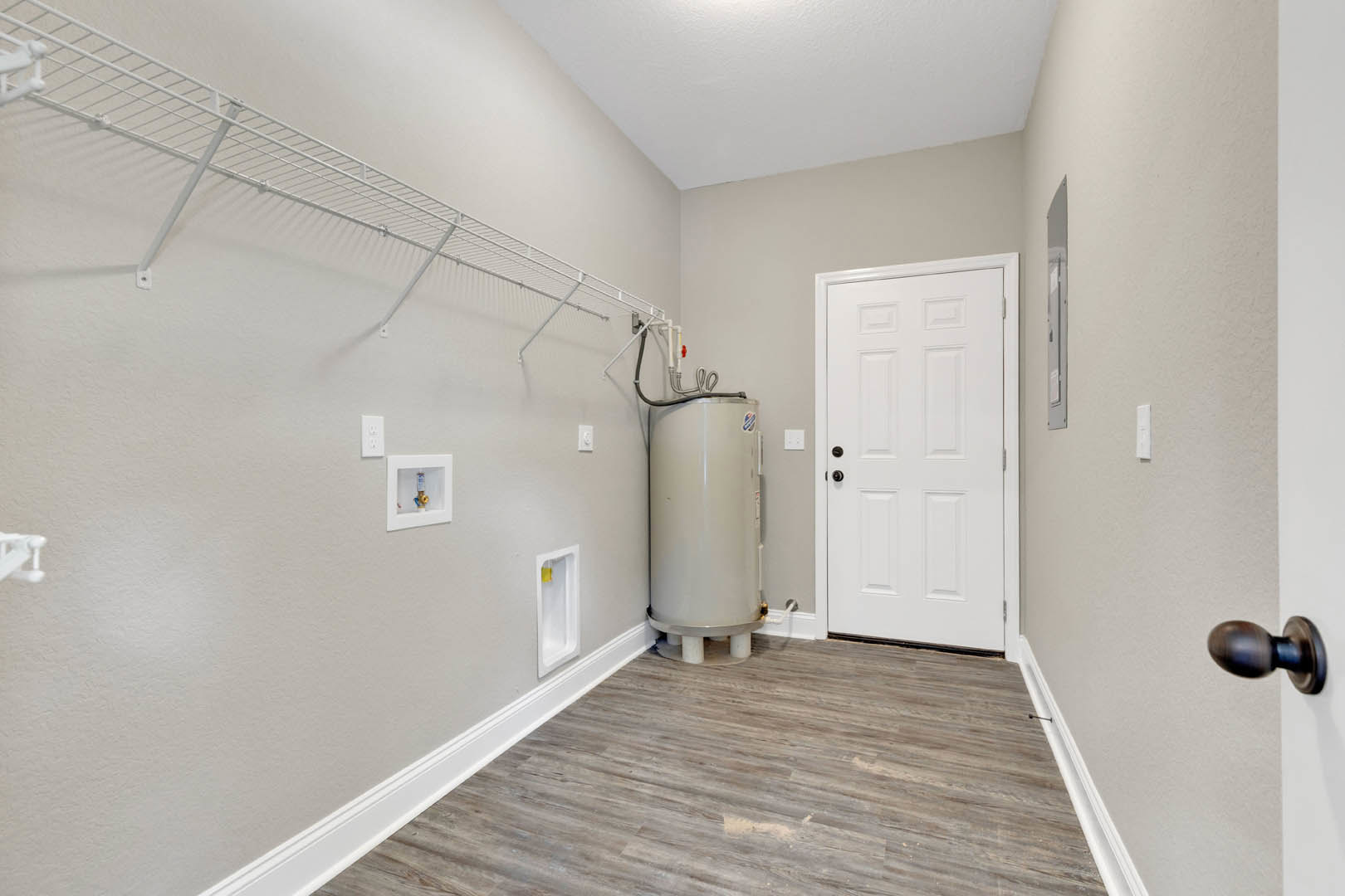 White paneled door with black knobs set in a white plaster wall, wood flooring with white baseboard trim, cylindrical white object with handle near door, close-up of door hardware
