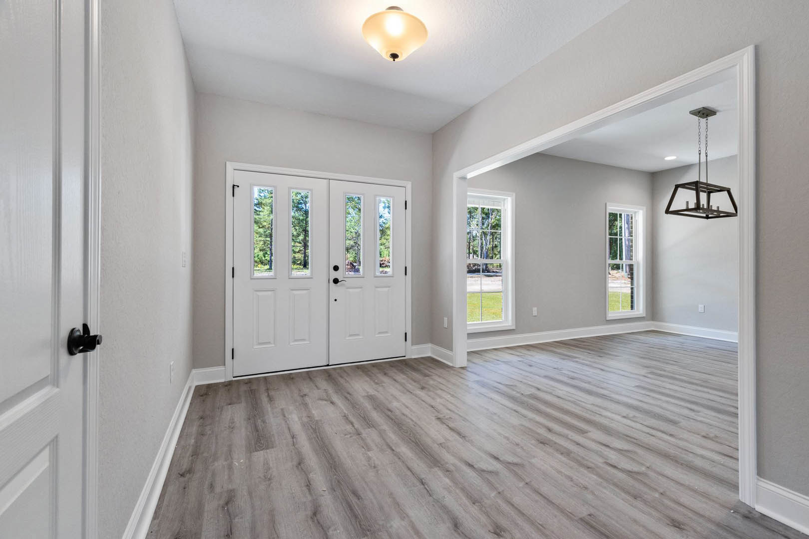White double doors with glass panes, hardwood floors, ceiling light fixture, and white walls with crown molding