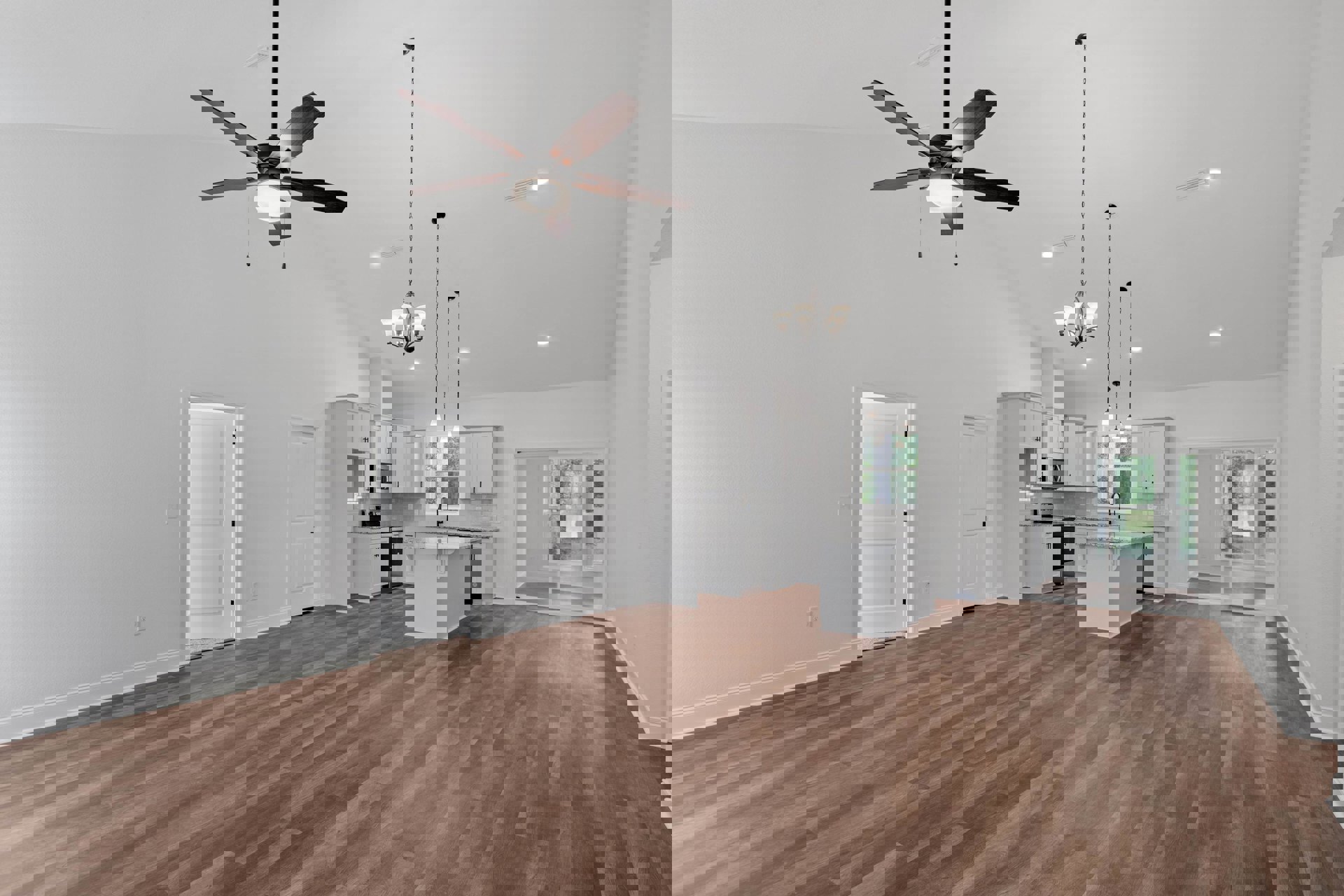 Spacious white room with wood flooring, ceiling fan with light, white kitchen island topped with marble, black refrigerator, sliding glass door, and white interior door