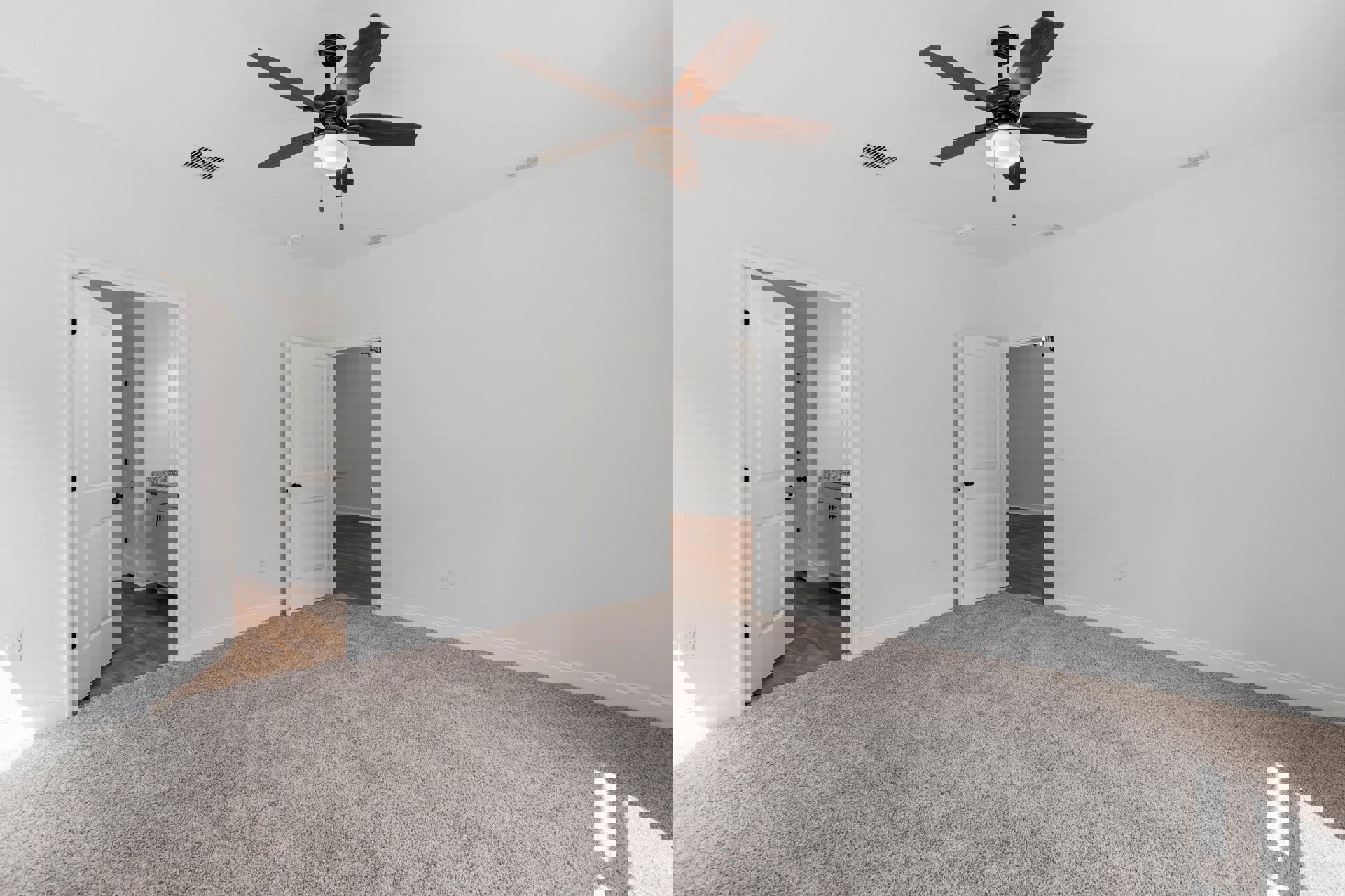 Carpeted bedroom with ceiling fan and light, white door with black knob open to bathroom, neutral walls and trim